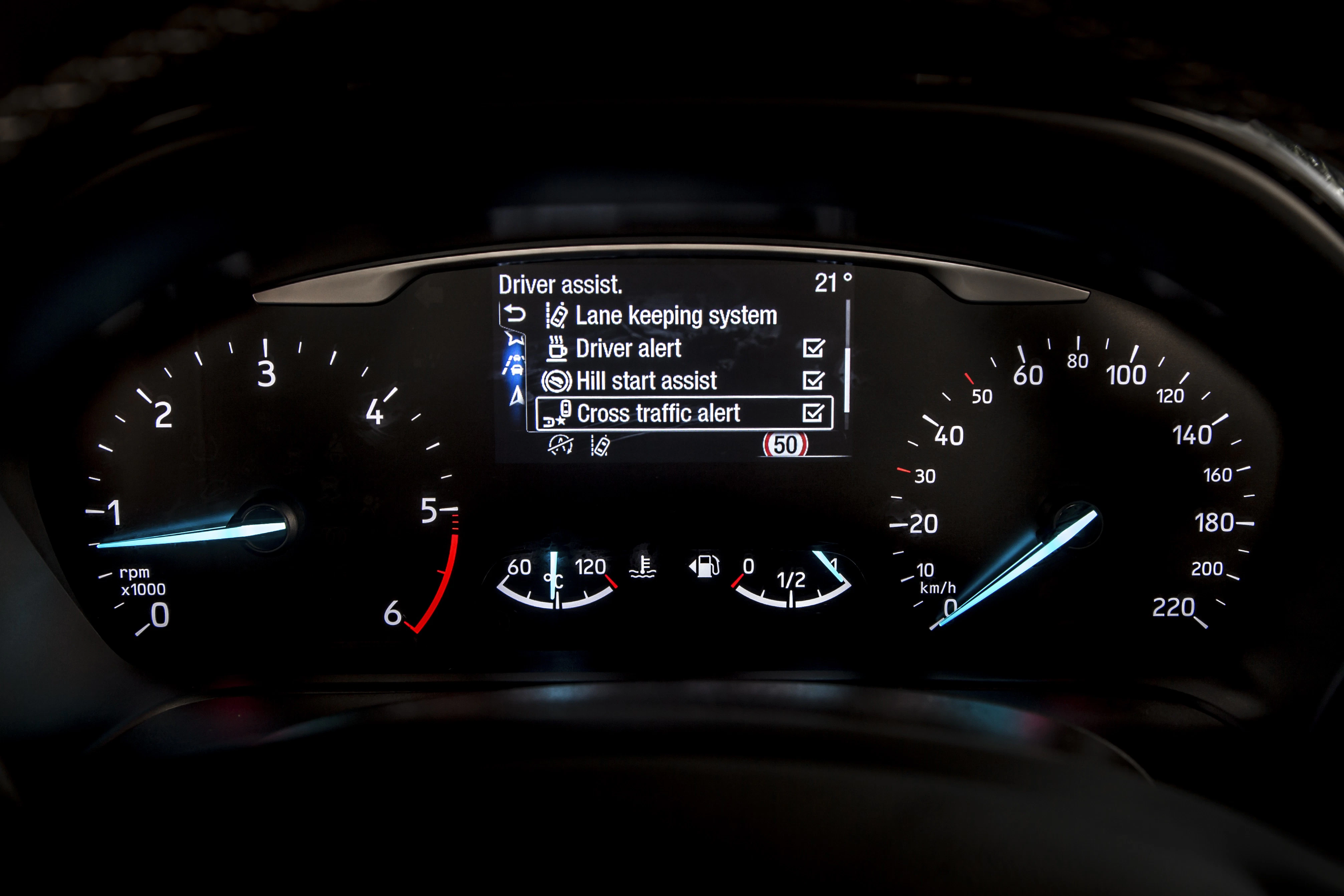 Nahaufnahme eines Autotachometers mit analogem Drehzahlmesser und Geschwindigkeit sowie digitaler Anzeige von Fahrerassistenzsystemen und Temperatur.