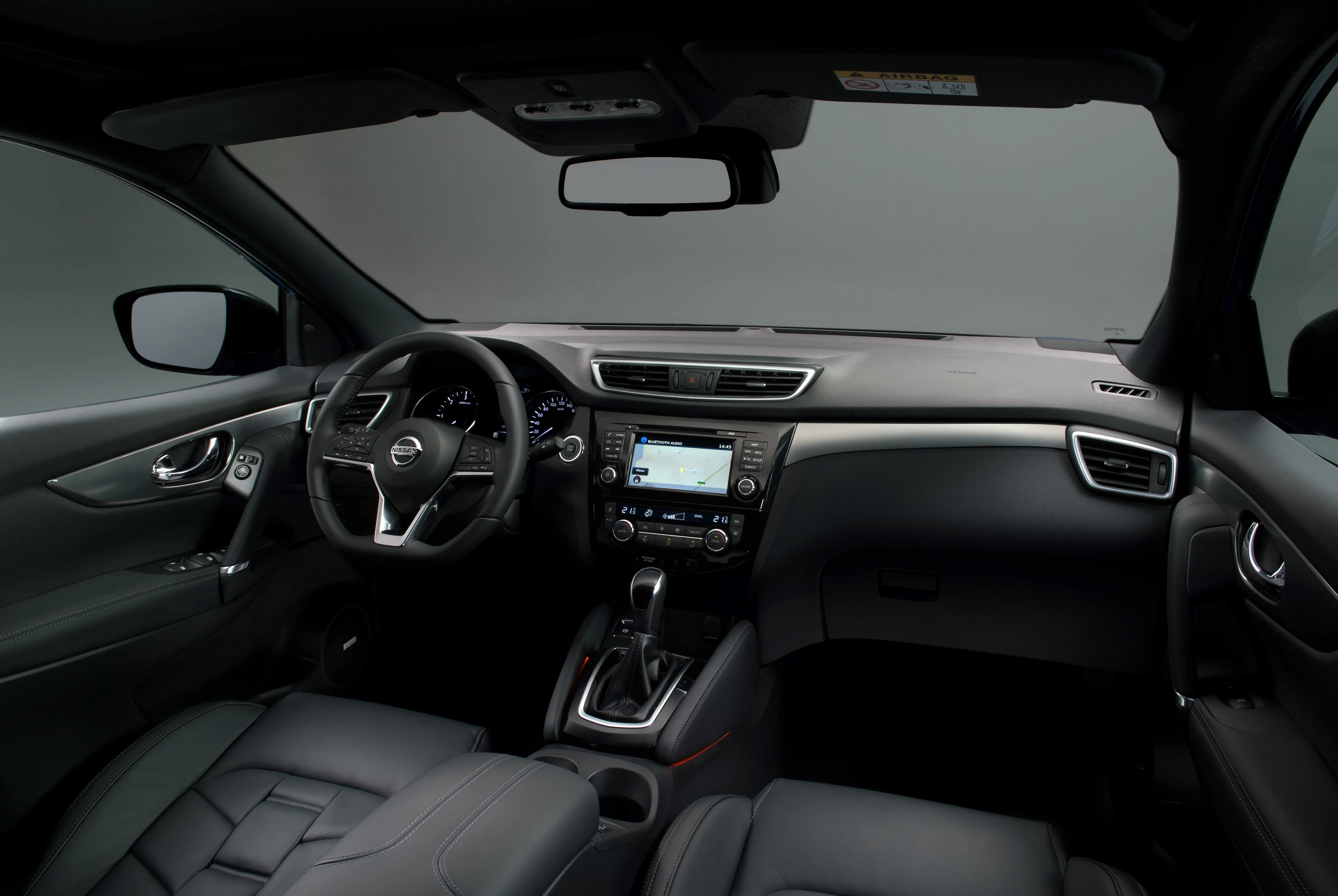 Innenraum eines modernen Autos, Blick auf Armaturenbrett mit integriertem Touchscreen, Lenkrad und Schalthebel. Schwarz-graues Interieur.