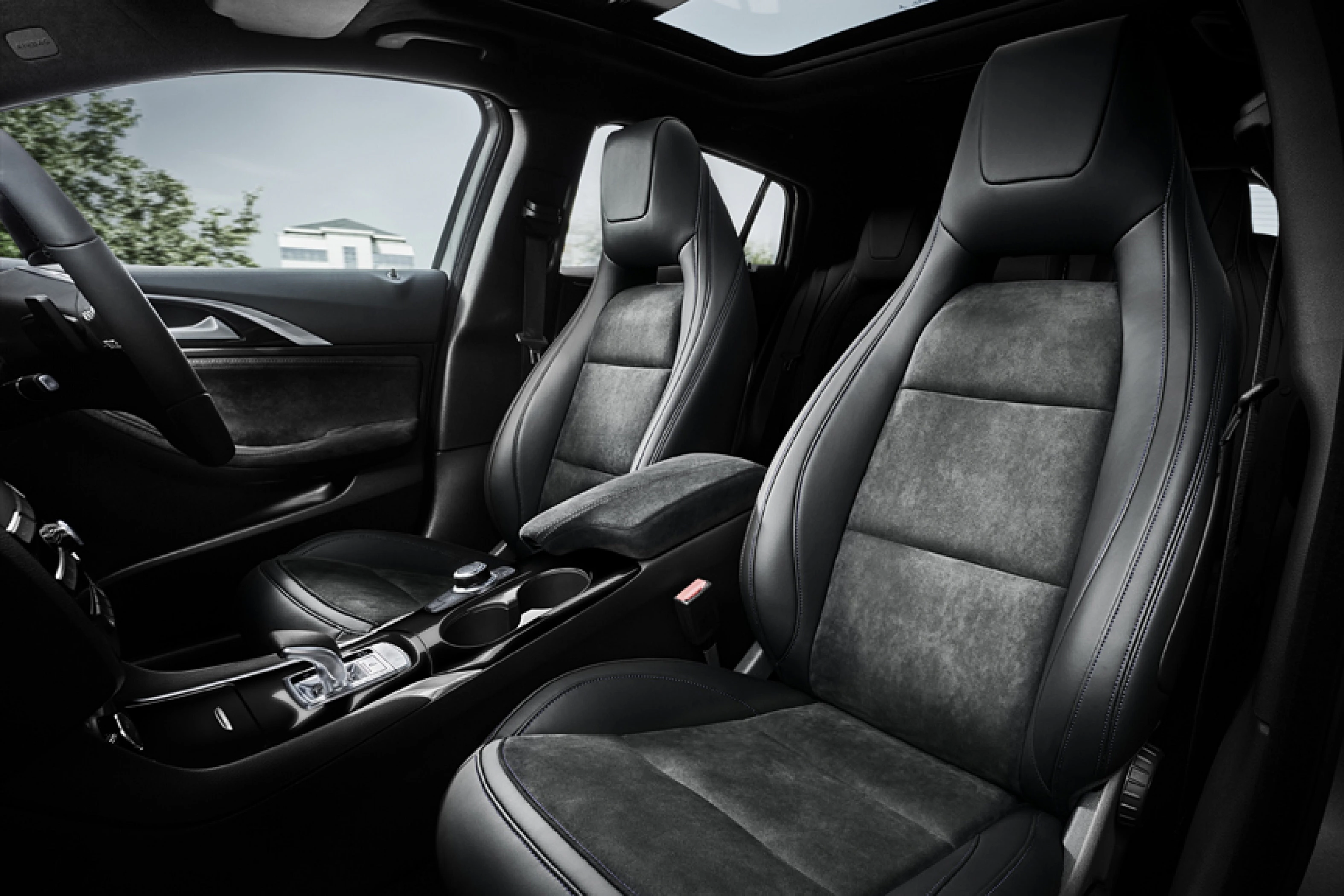 Innenraum eines Autos mit modernen, schwarzen Ledersitzen und einem Panoramaglasdach. Armaturenbrett und Mittelkonsole sind sichtbar.