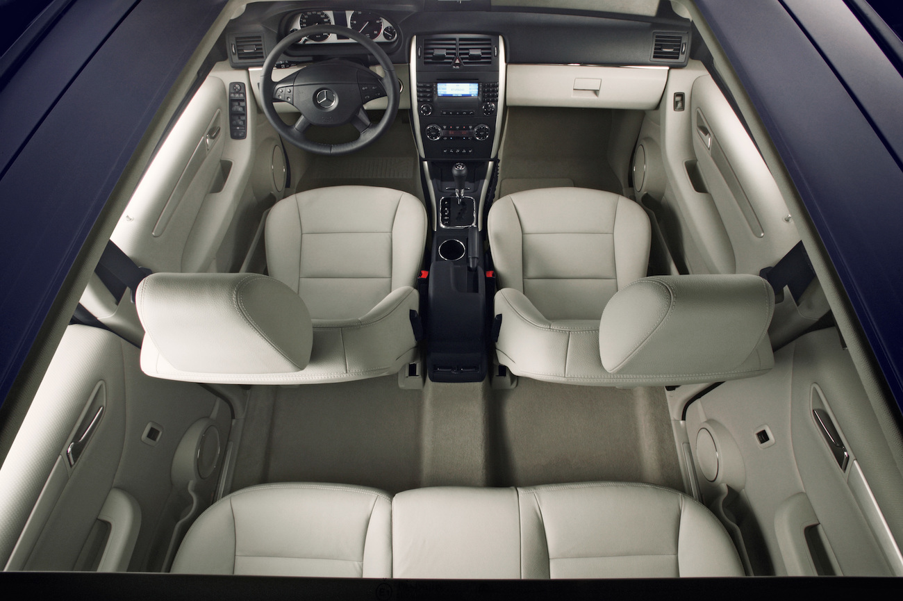Innenansicht eines Autos mit vier beigen Ledersitzen und zentraler Mittelkonsole, von oben fotografiert.