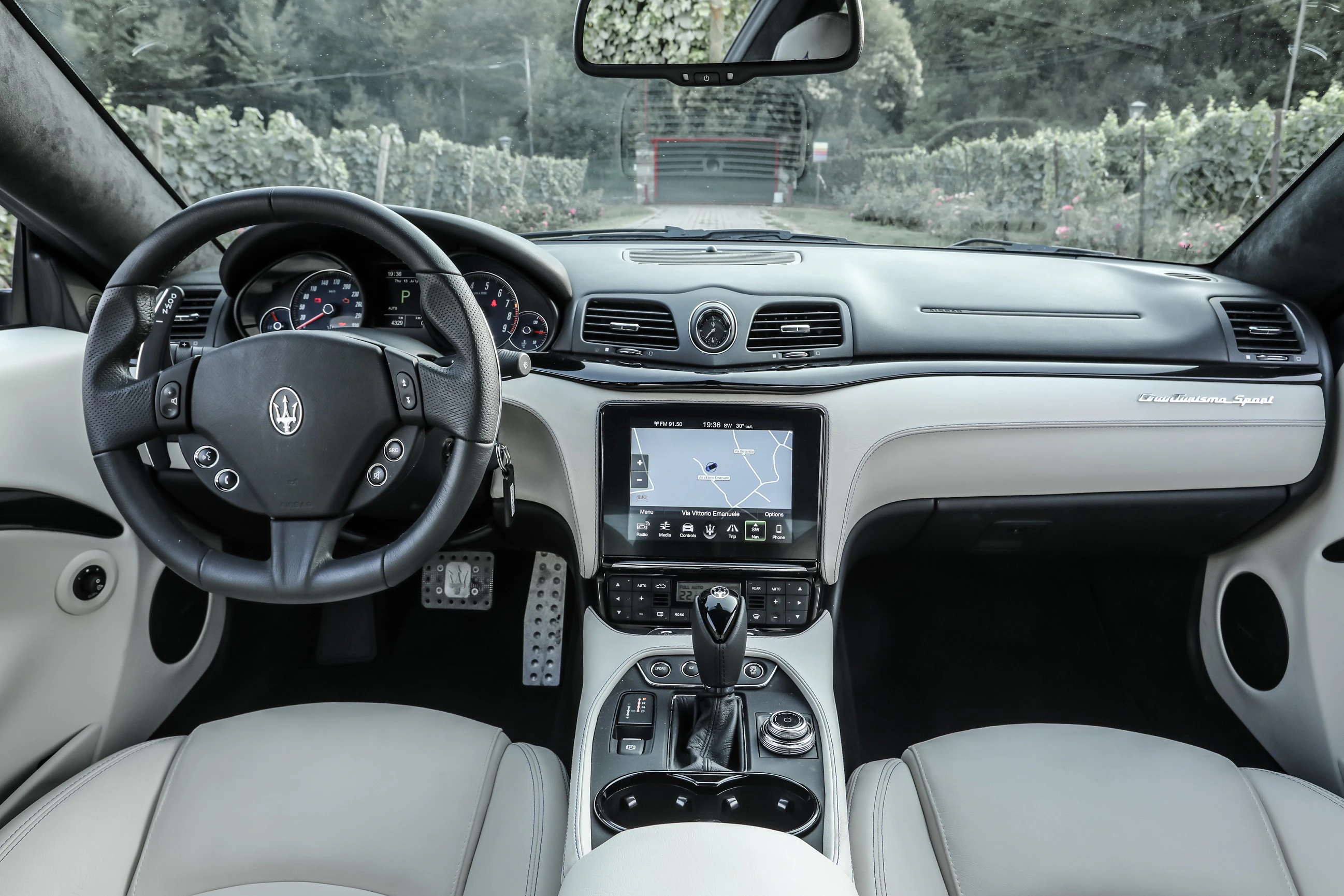 Innenraum eines Luxusautos mit Lederpolstern, Multifunktionslenkrad, Navigationsdisplay und edlen Armaturen.