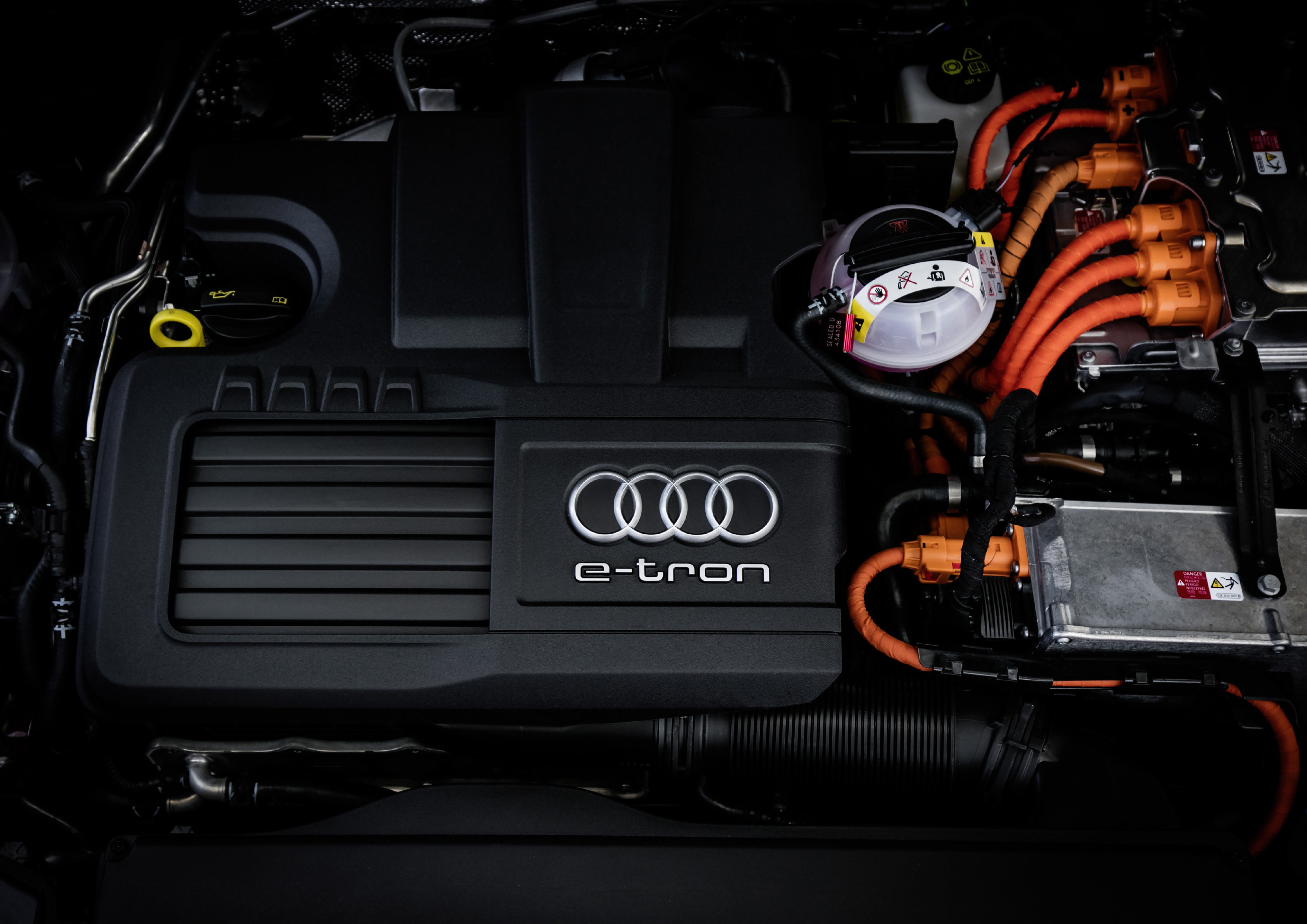 Nahaufnahme eines Audi e-tron Motorraums mit sichtbaren Komponenten und orangefarbenen Kabeln.