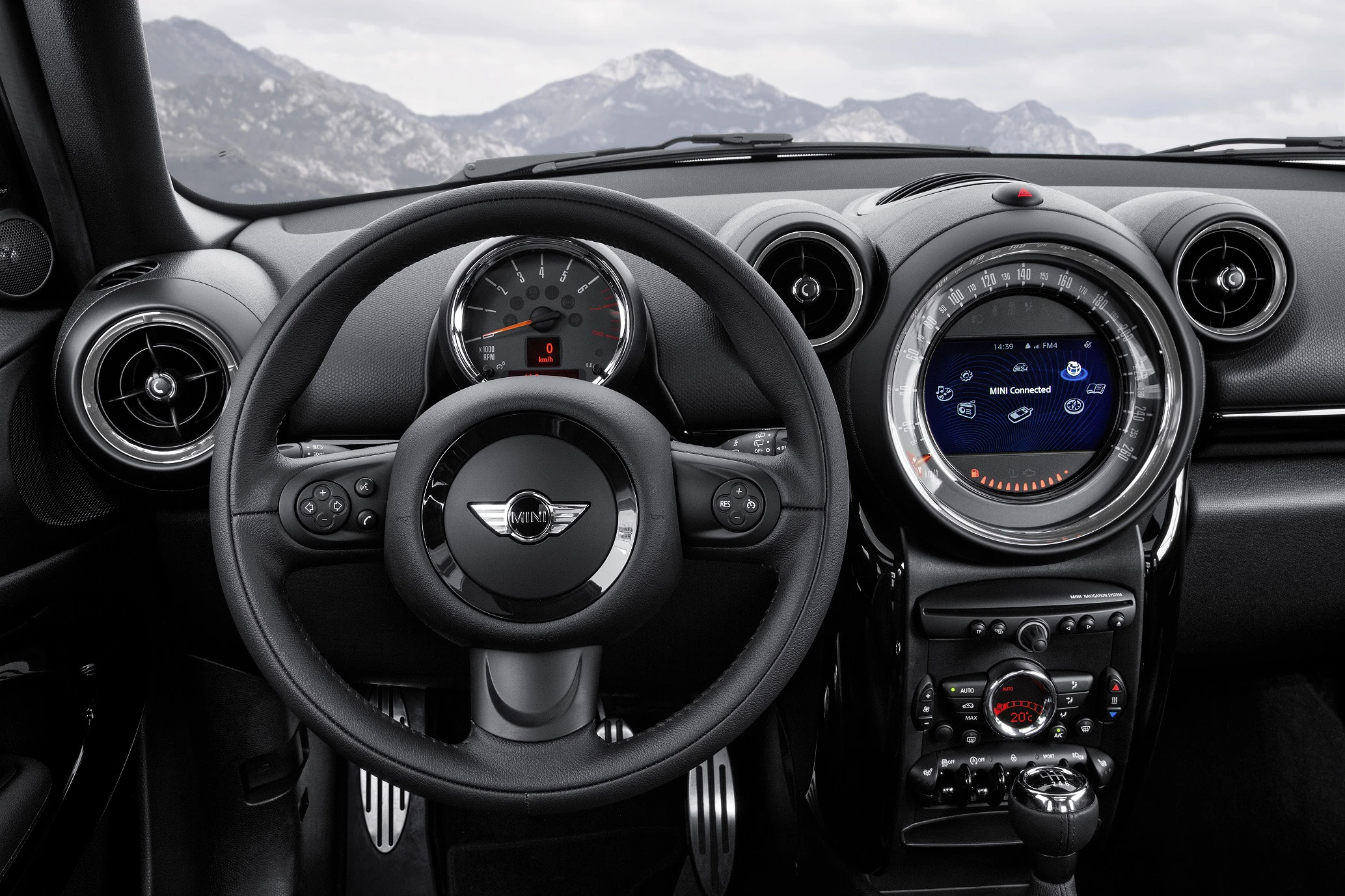 Innenraum eines Autos mit Kombiinstrument und Lenkrad, Blick auf die Berge im Hintergrund. Modernes Design mit rundem Tacho und Bildschirm.