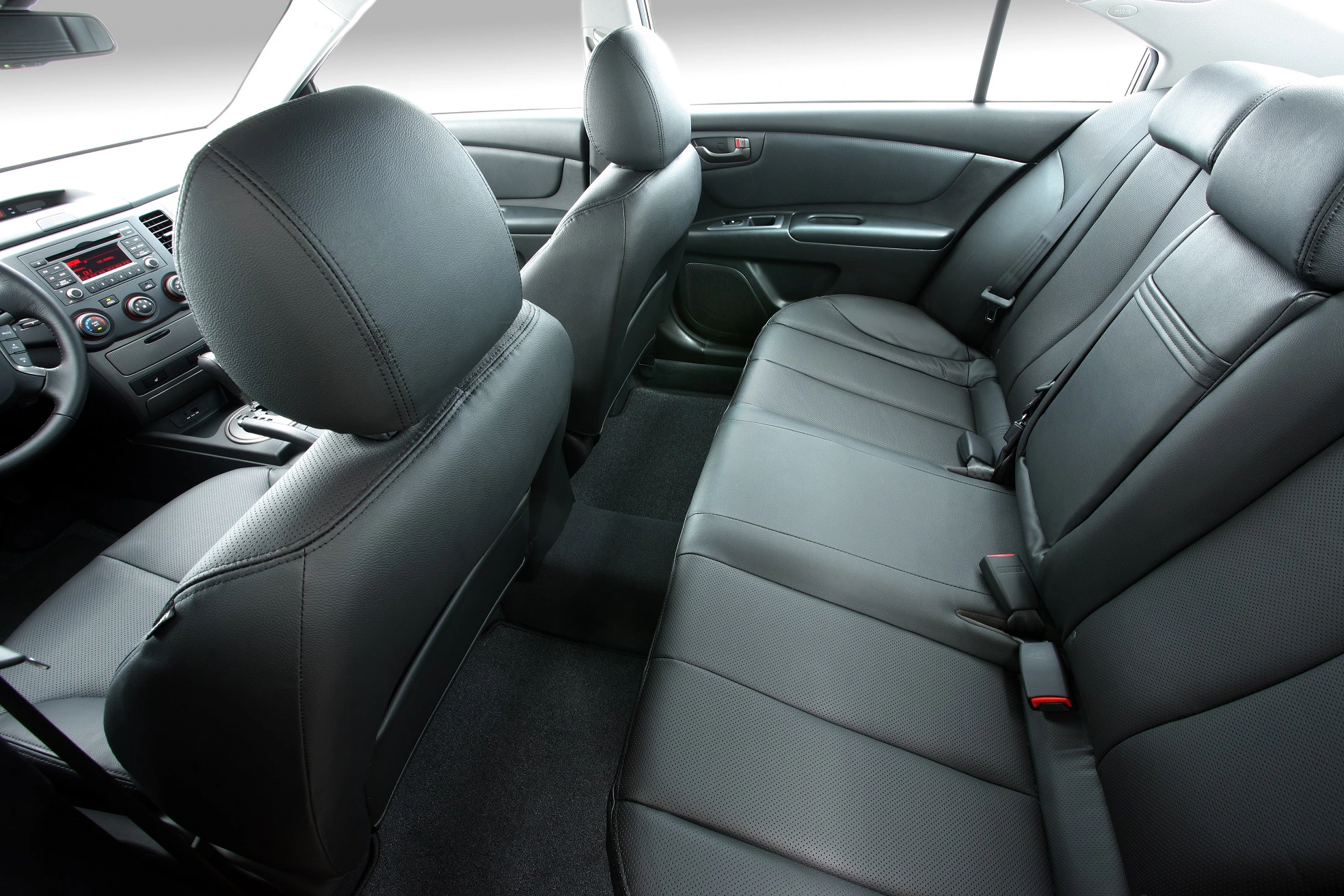 Innenraum eines Autos mit schwarzen Ledersitzen und modernem Armaturenbrett. Bequem gestalteter Rücksitzbereich mit Sicherheitsgurten.