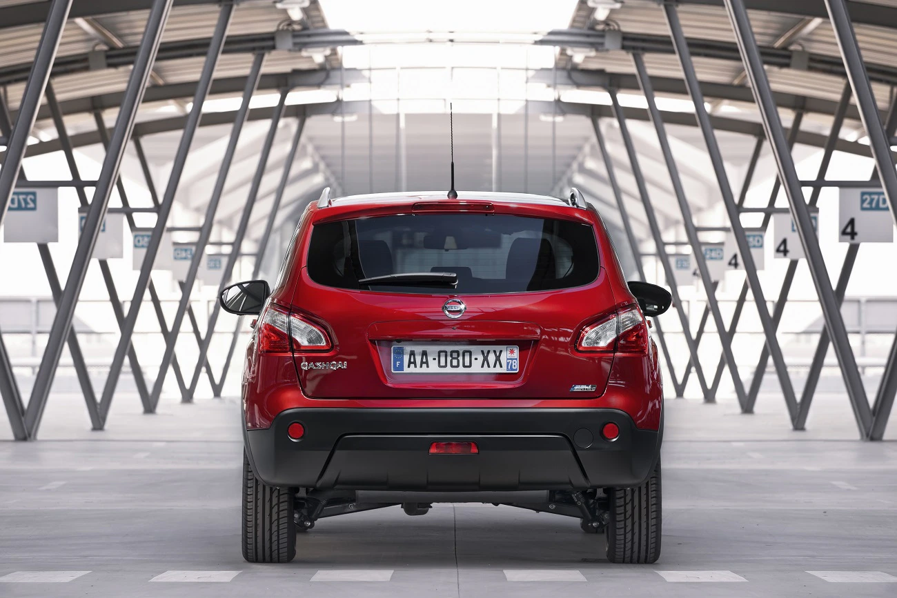 Roter Nissan Qashqai von hinten in einem modernen, überdachten Parkbereich mit stahlgrauen Strukturen und nummerierten Parkplätzen.