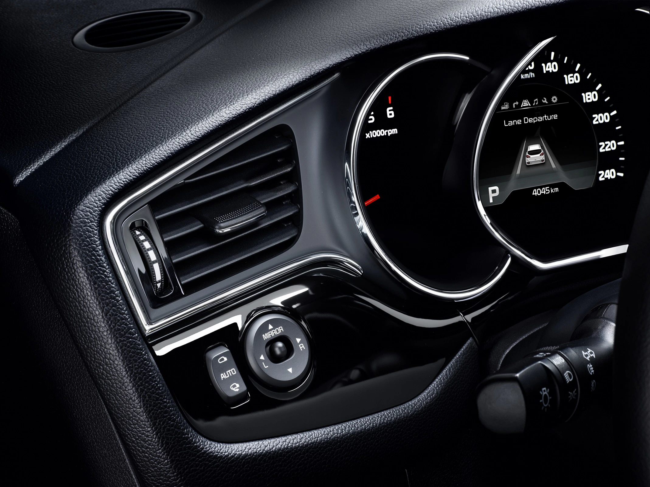 Nahaufnahme eines Autos mit Tachometer und Lüftungsschlitzen. Der Tacho zeigt Geschwindigkeit und Fahrinformationen auf einem digitalen Display an.