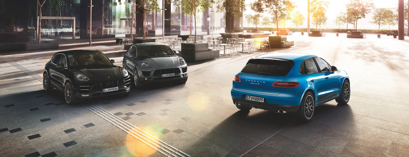 Drei Porsche-SUVs stehen auf einem städtischen Platz bei Sonnenaufgang, umgeben von modernen Gebäuden und Bäumen.