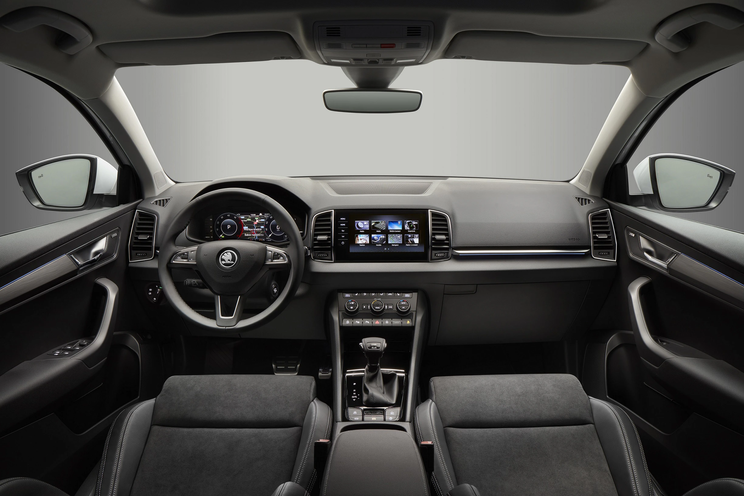 Innenraum eines Autos mit modernem Armaturenbrett, Multifunktionslenkrad, großem Display und bequemen Sitzen in dunklen Farben.
