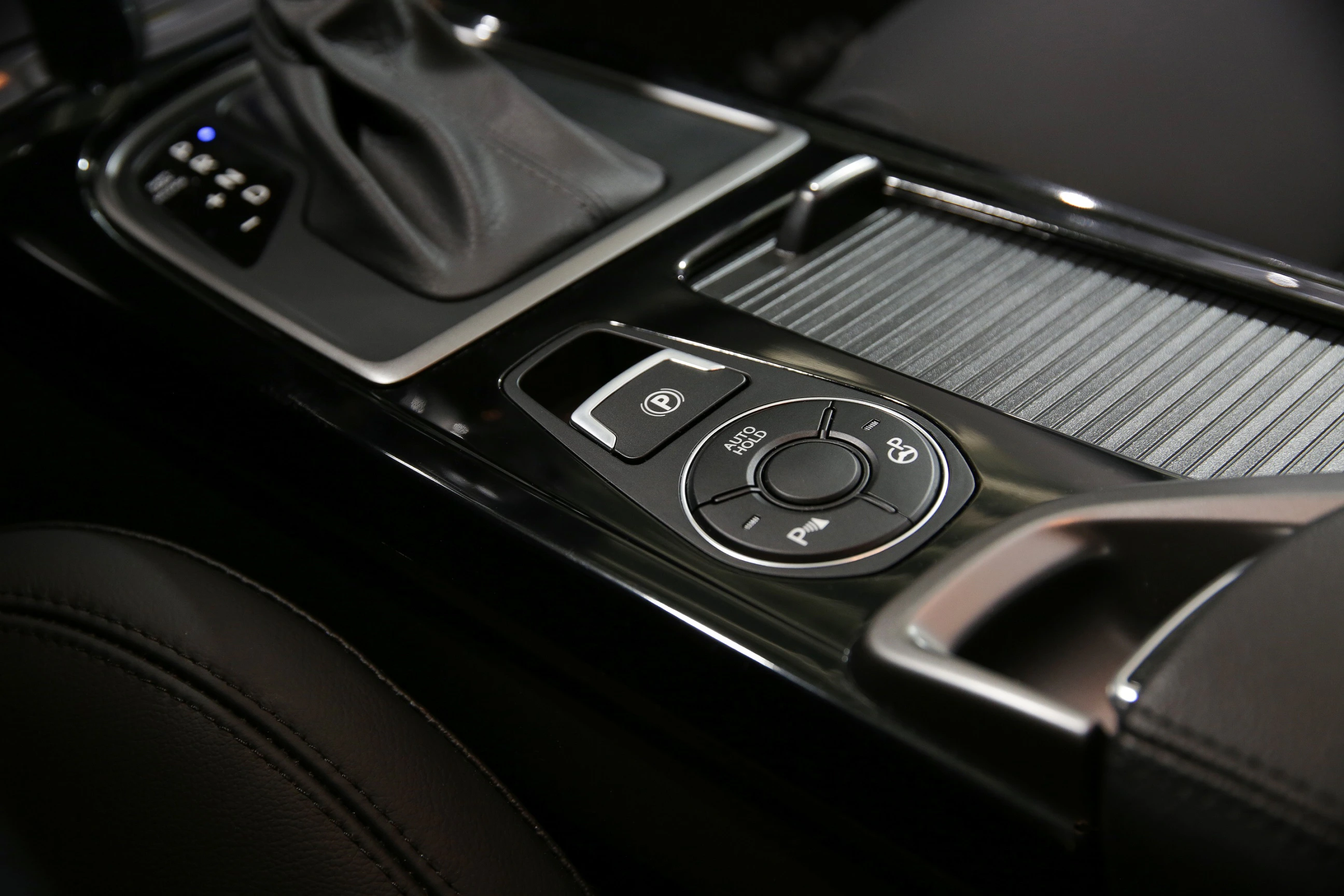 Nahaufnahme einer Mittelkonsole in einem Auto mit Schalthebel, elektronischer Handbremse und Bedienelementen für Fahrmodi.