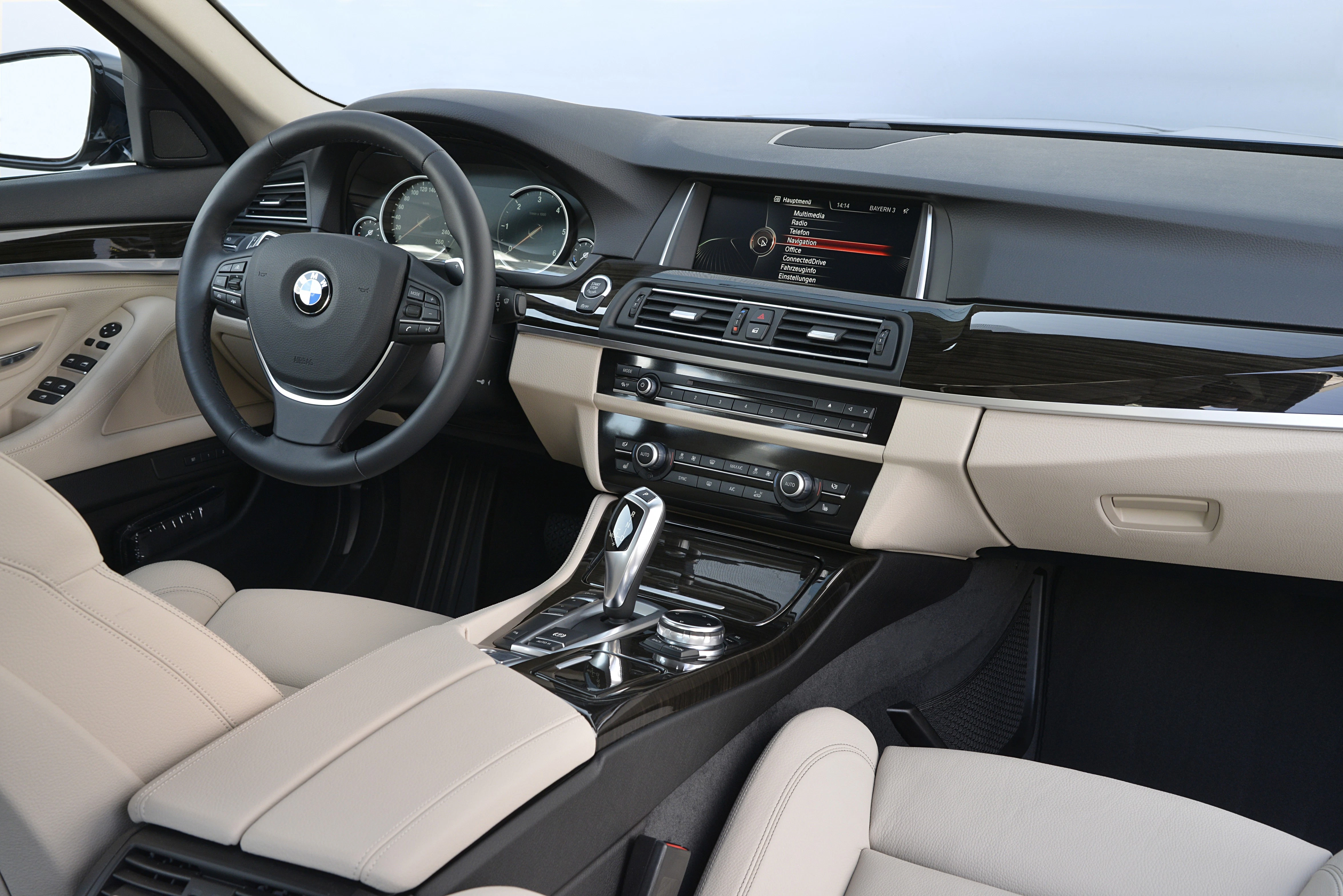 BMW-Innenraum mit modernem Armaturenbrett, Lederpolsterung, zentralem Display und glänzenden Akzentleisten.