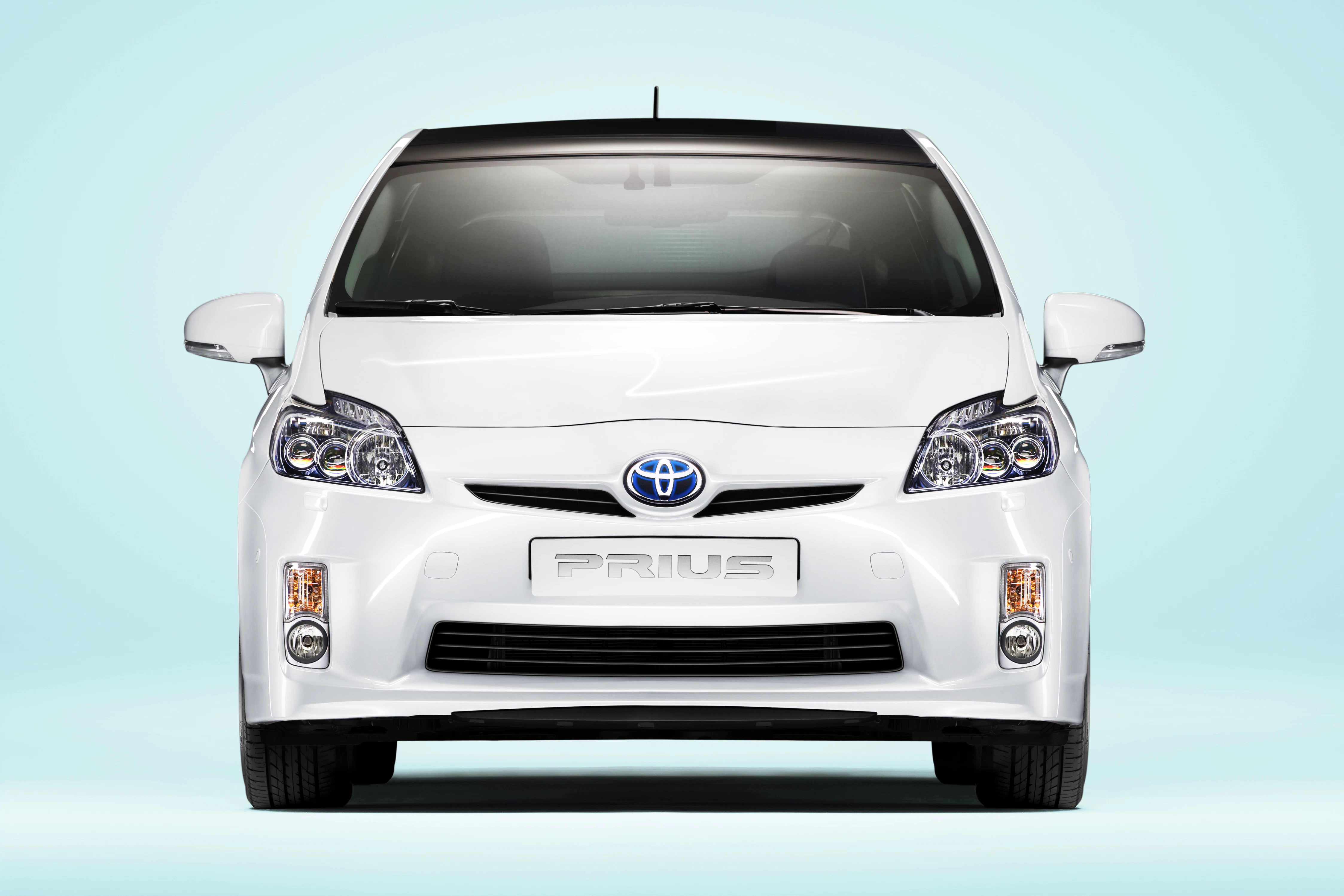 Weißer Toyota Prius von vorne mit hellblauem Hintergrund.