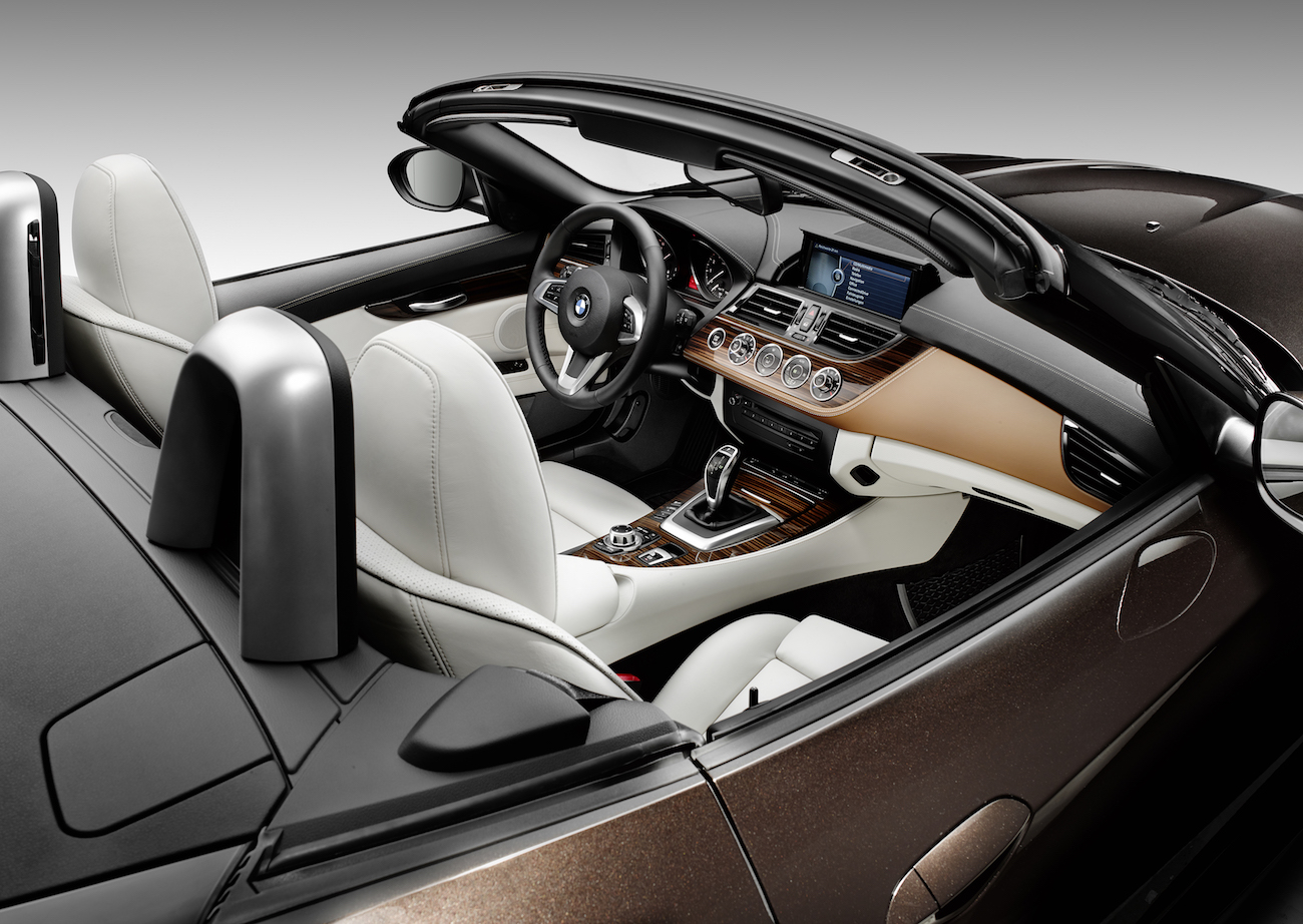 Luxuriöses Cabriolet mit beigem Lederinterieur, Holzverkleidung, modernen Technik-Features und offenem Verdeck, Ansicht von oben.