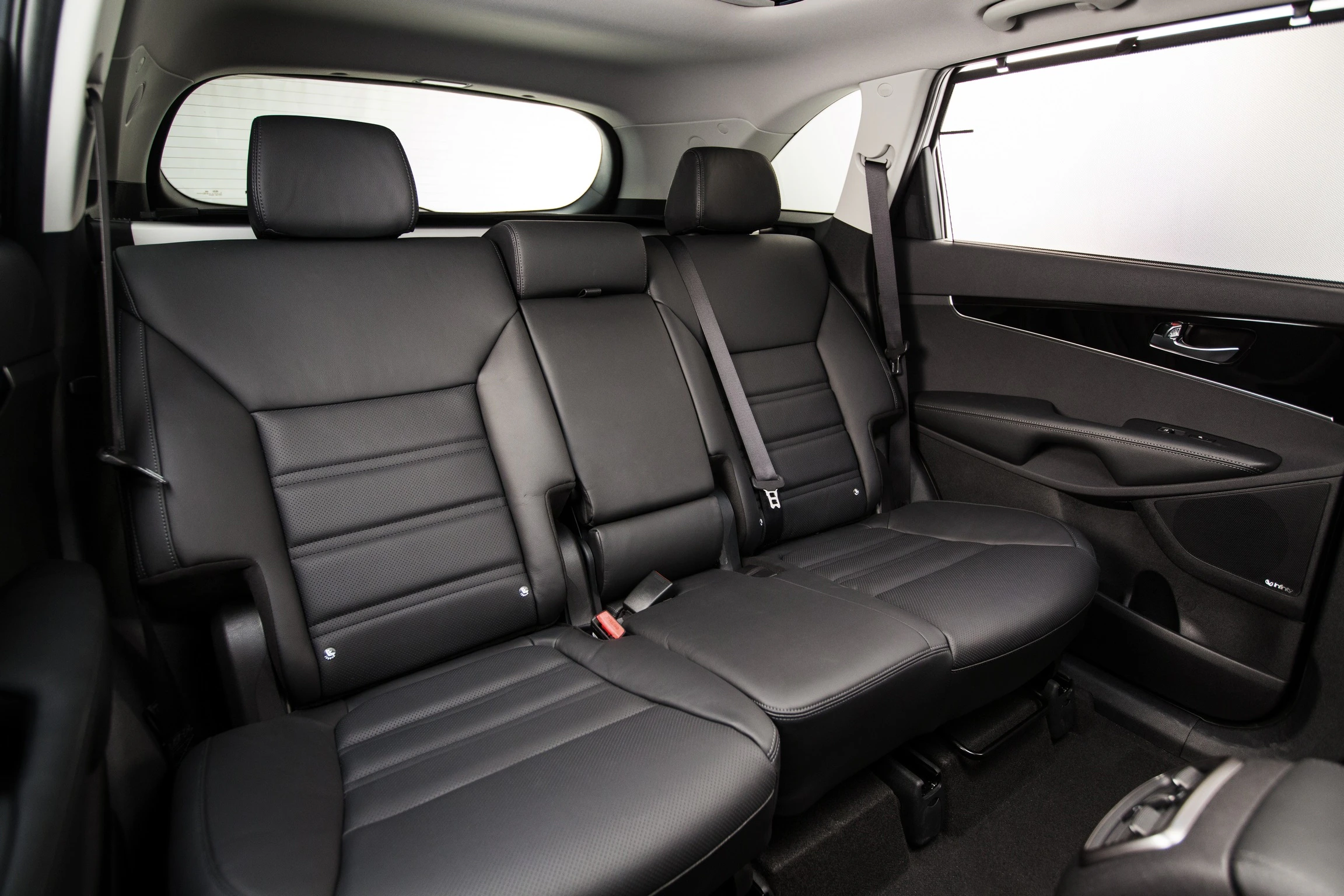 Rücksitze eines Autos mit schwarzer Lederpolsterung, drei Kopfstützen und Sicherheitsgurten in einem modernen Fahrzeuginterieur.