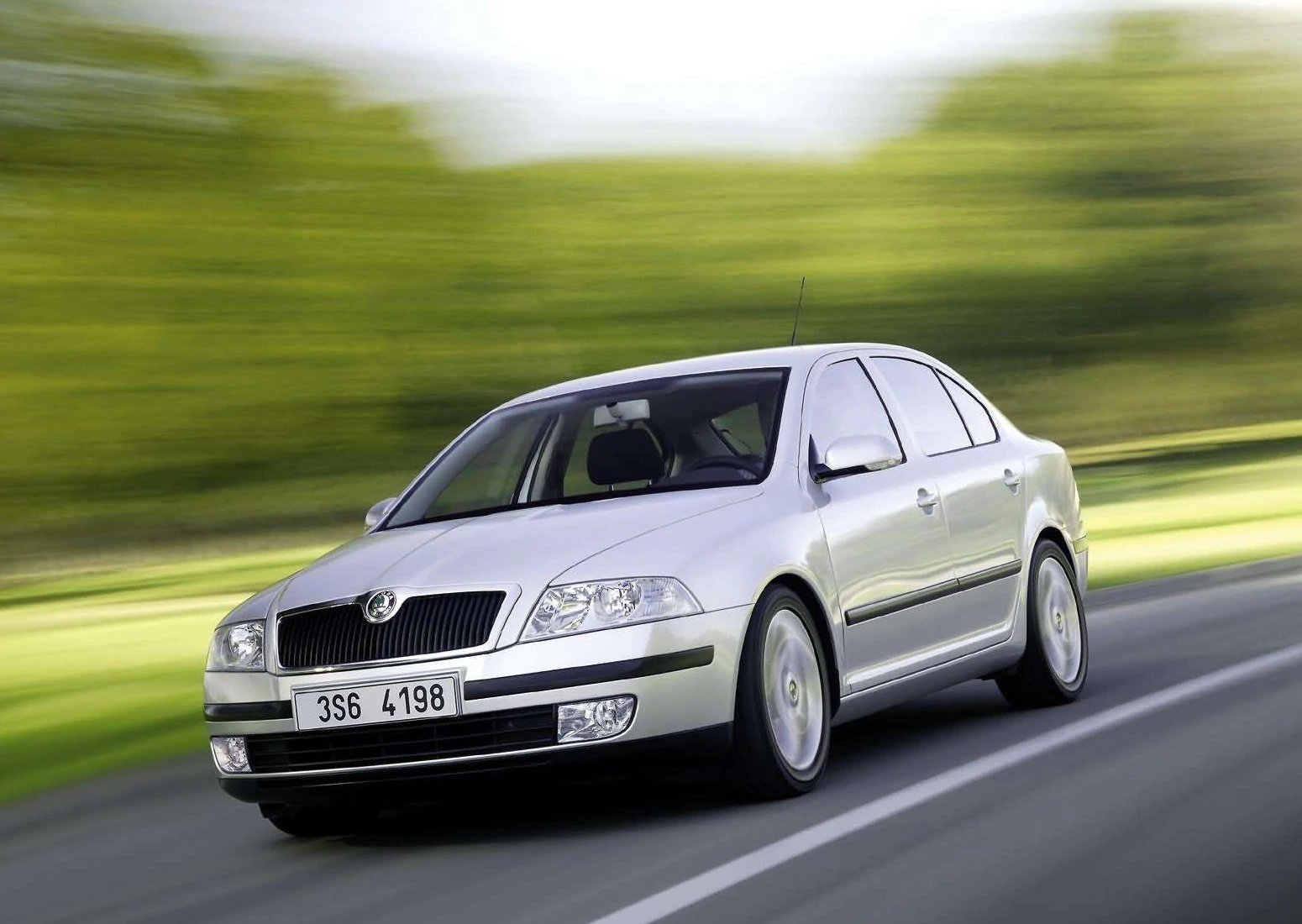 Silberner Skoda Octavia fährt auf einer Landstraße, umgeben von unscharfer, grüner Landschaft in Bewegung.