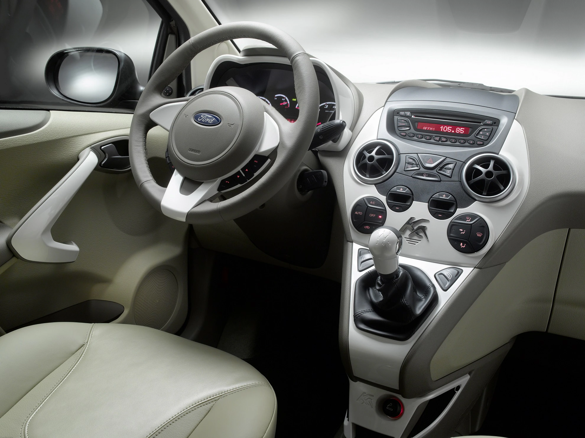 Innenraum eines Autos mit beigem Interieur. Sicht auf Lenkrad, Armaturenbrett mit Rundinstrumenten und Schaltknüppel.