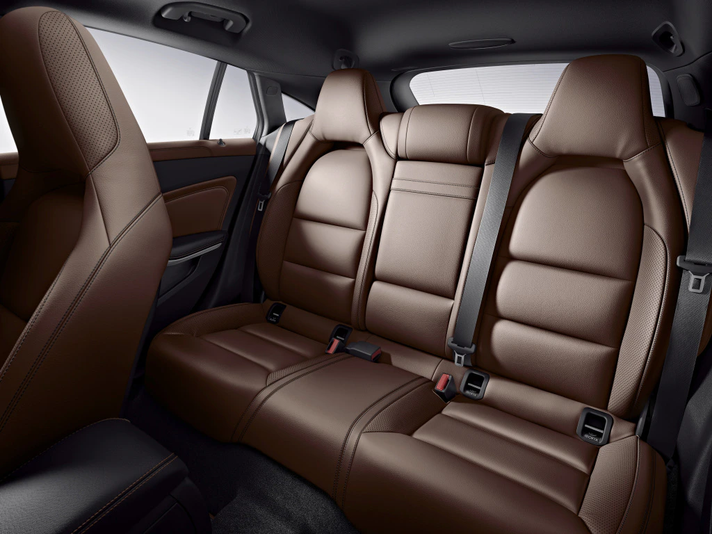 Rückbank eines Autos mit braunen Ledersitzen, drei Kopfstützen, Sicherheitsgurten und schickem, modernem Design.