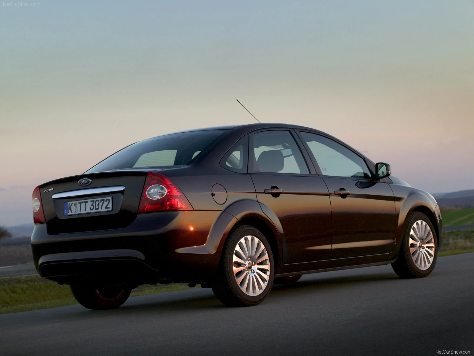 Schwarzer Ford Focus Limousine auf einer Landstraße im Sonnenuntergang, von hinten fotografiert.