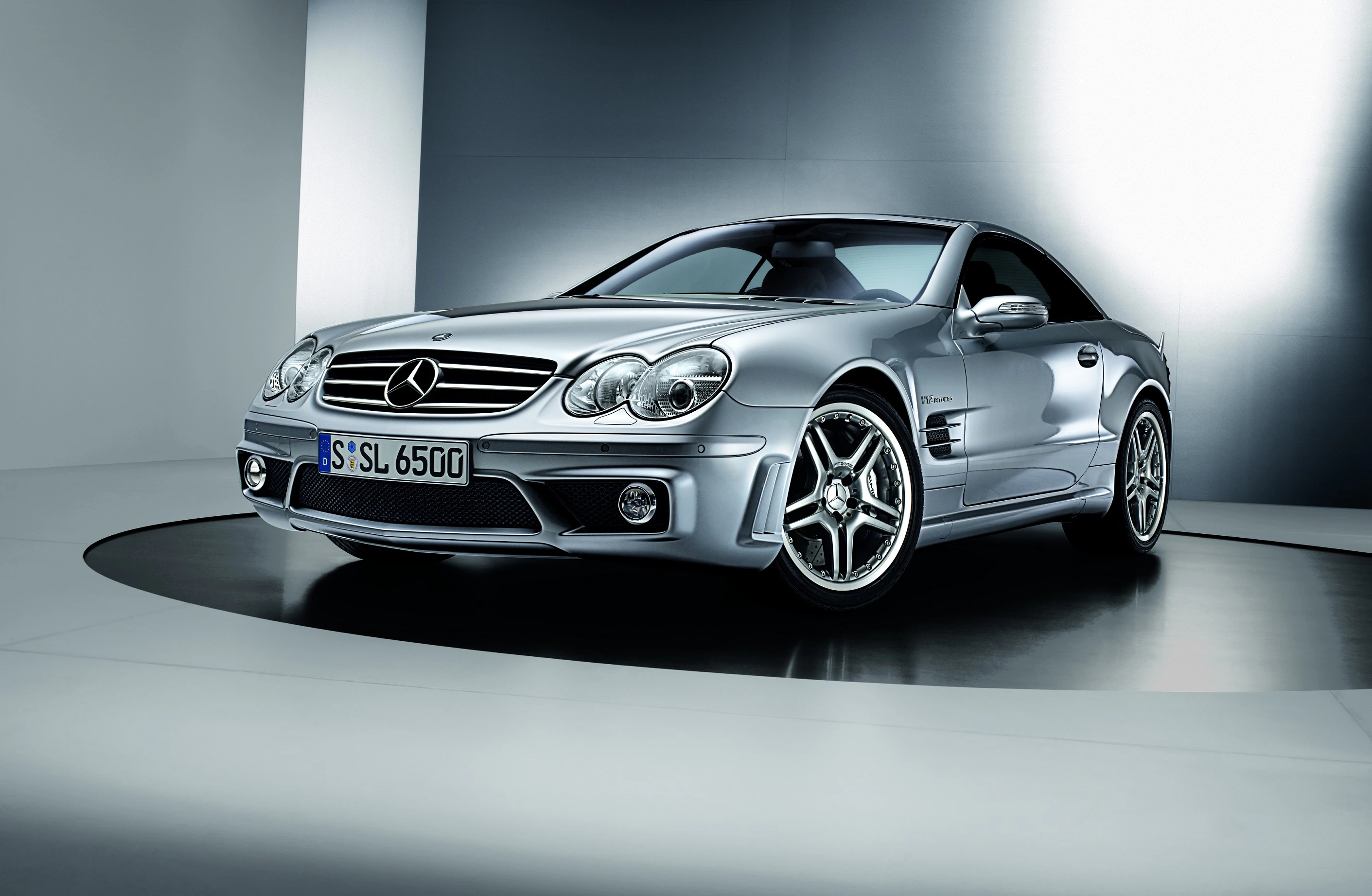 Silberner Mercedes-Benz Sportwagen steht in modernem, beleuchtetem Raum auf rundem Podest. Elegantes, aerodynamisches Design.
