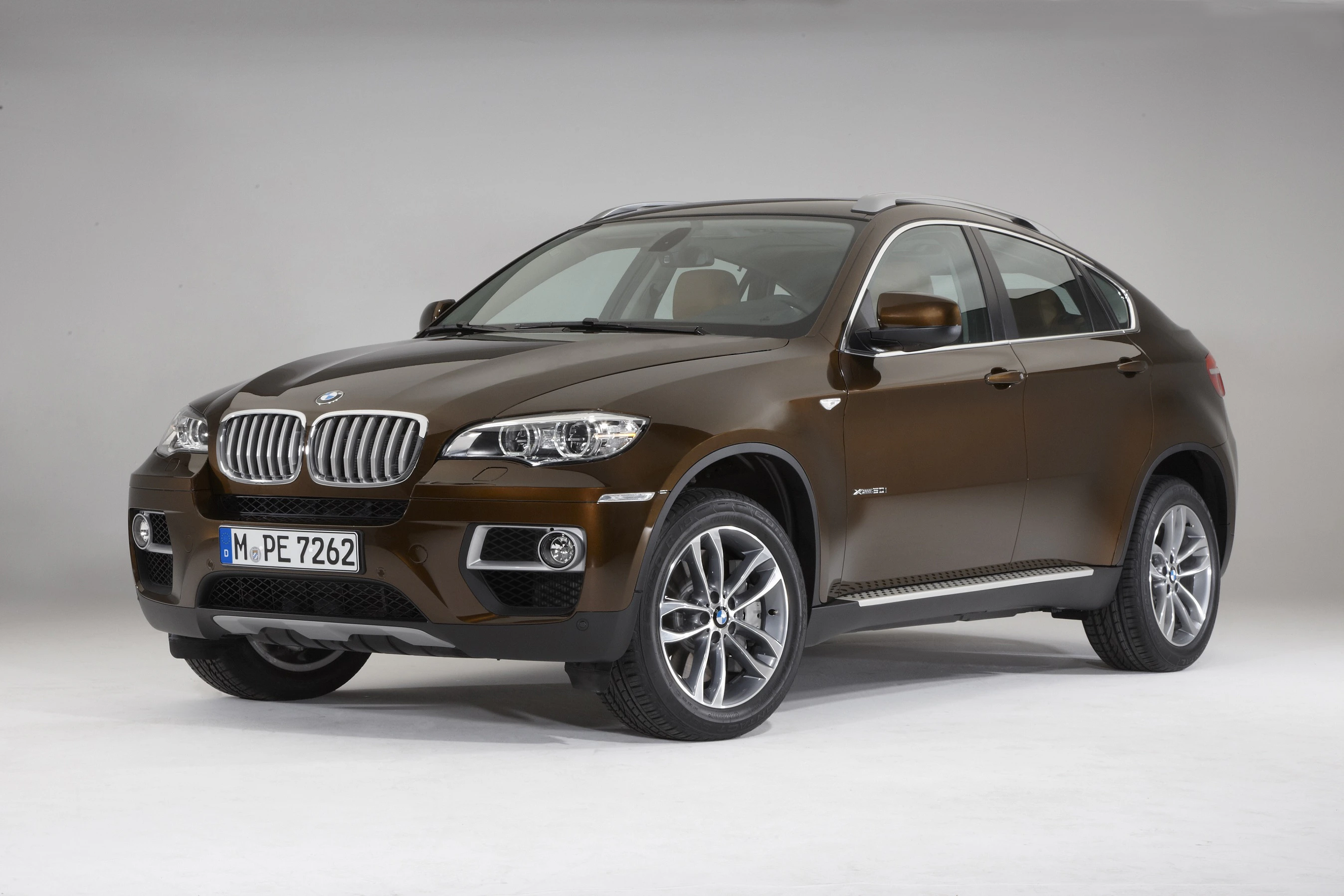 Dunkelbrauner BMW X6 SUV auf neutralem Hintergrund, schräg von vorne fotografiert. Das Auto hat silberne Felgen und eine sportliche Karosserieform.