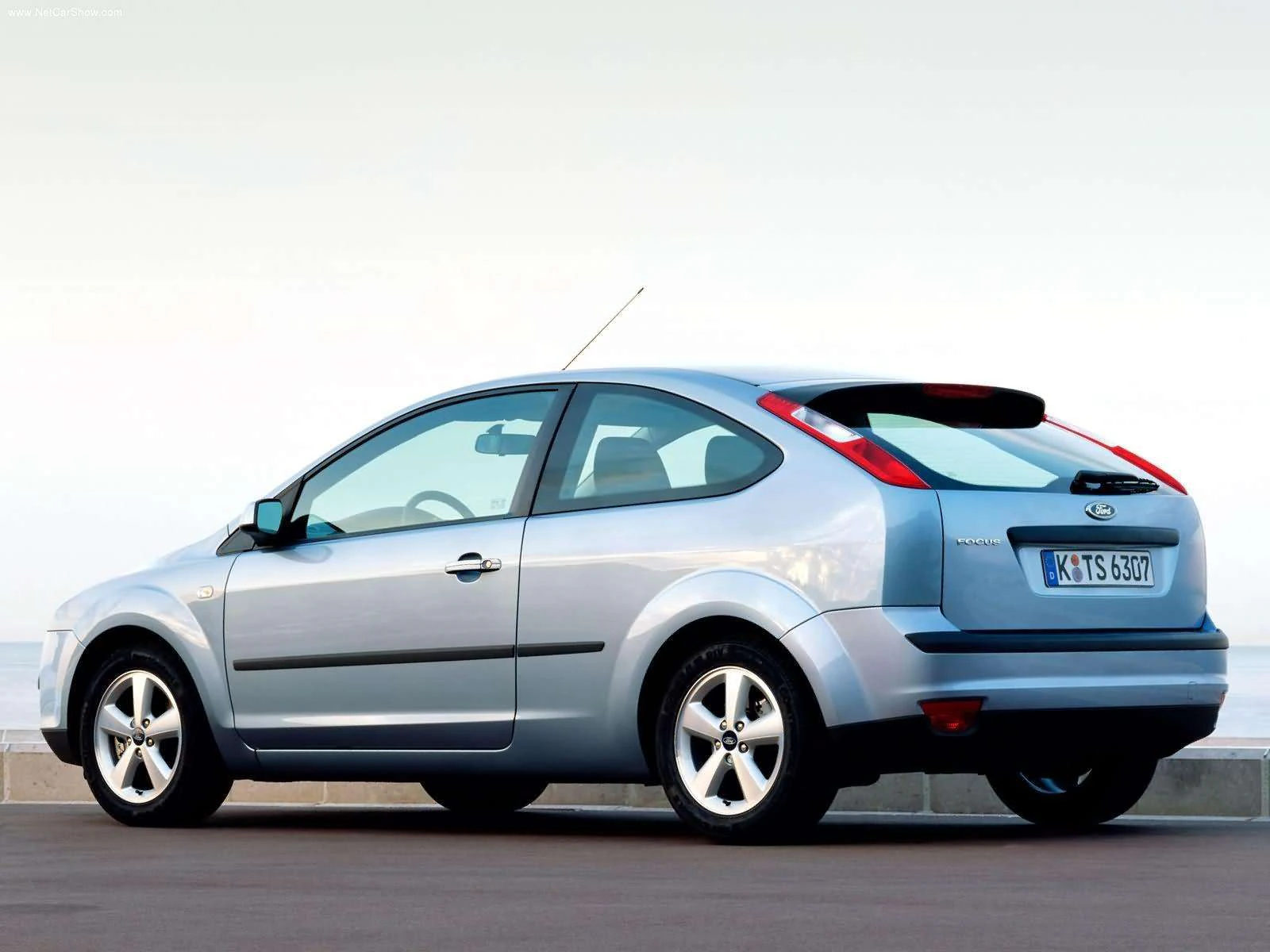 Silberner Ford Focus Kompaktwagen, Seitenansicht, geparkt auf einer Straße, mit hellem Himmel im Hintergrund.