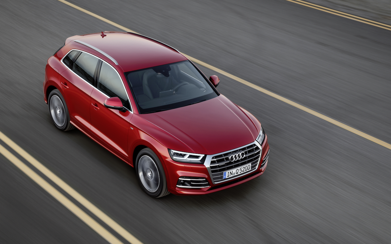 Roter Audi Q5 fährt auf einer asphaltierten Straße mit gelben Linien, Ansicht von schräg oben.