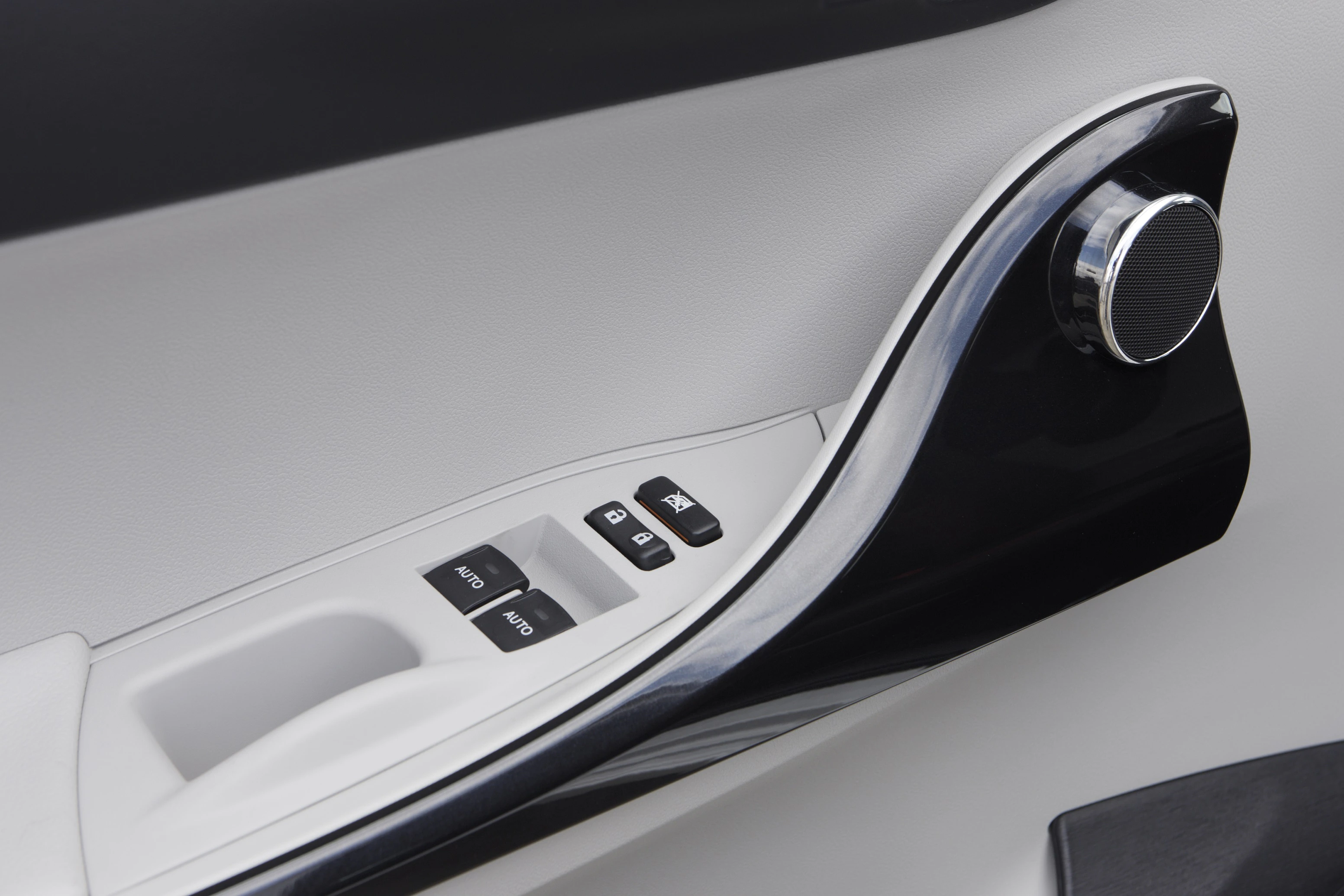 Nahaufnahme einer Autotürinnenverkleidung mit silbernem Türgriff und elektrischen Fensterbedienungen auf einem weißen Panel.