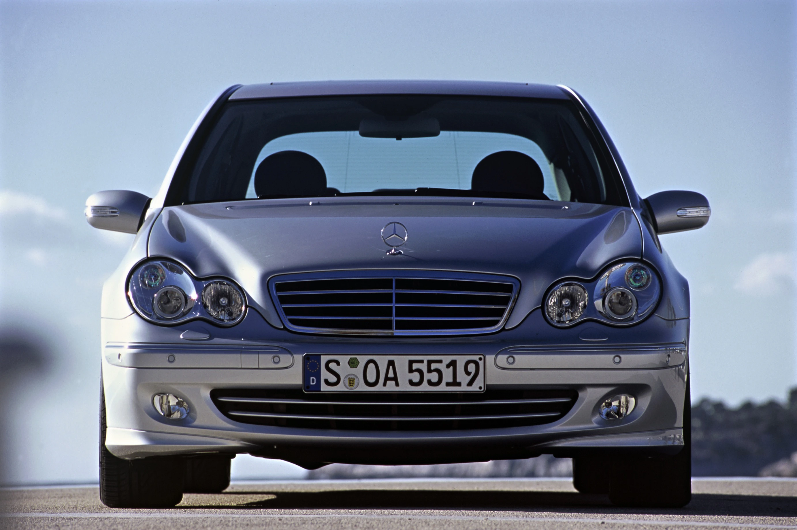 Silberner Mercedes-Benz-Limousine, Frontansicht, mit deutschen Kennzeichen, geparkt auf sonniger Straße.