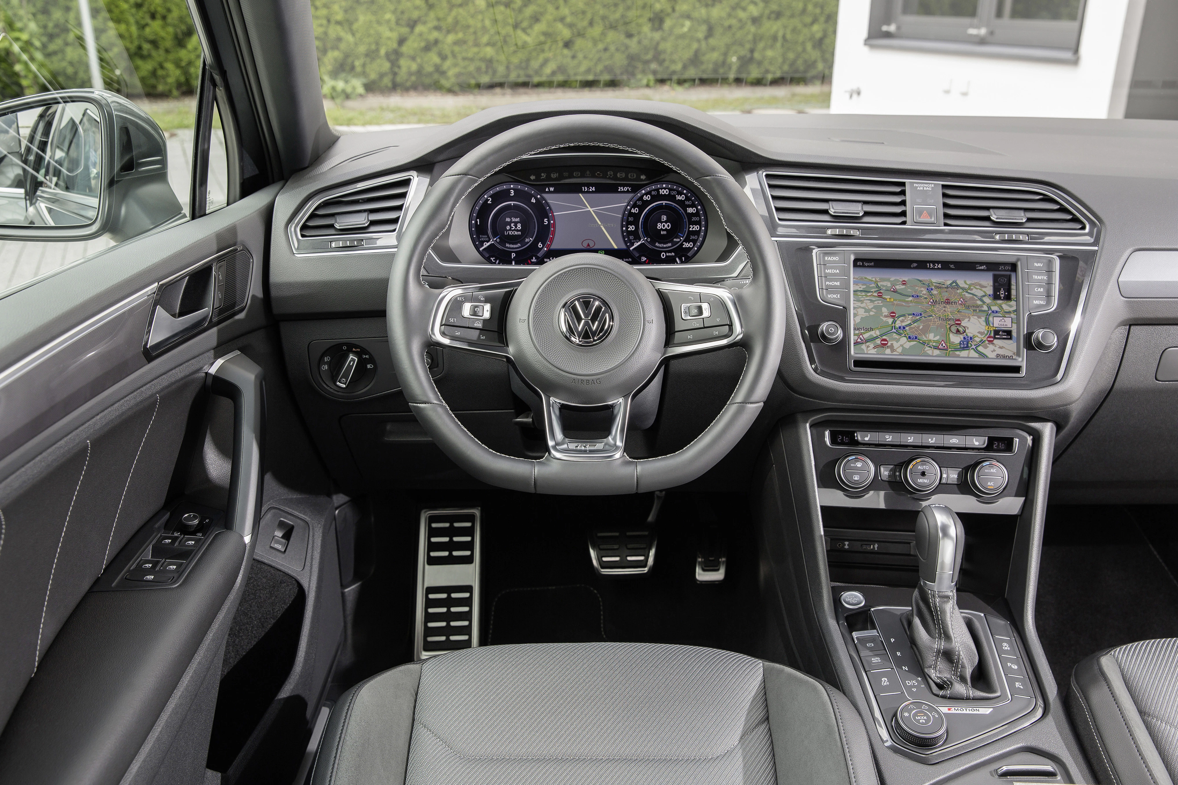 Innenraum eines VW-Autos mit einem modernen Cockpit, digitalem Display, Navigationssystem und Automatikgetriebe. Elegante, graue Lederausstattung.