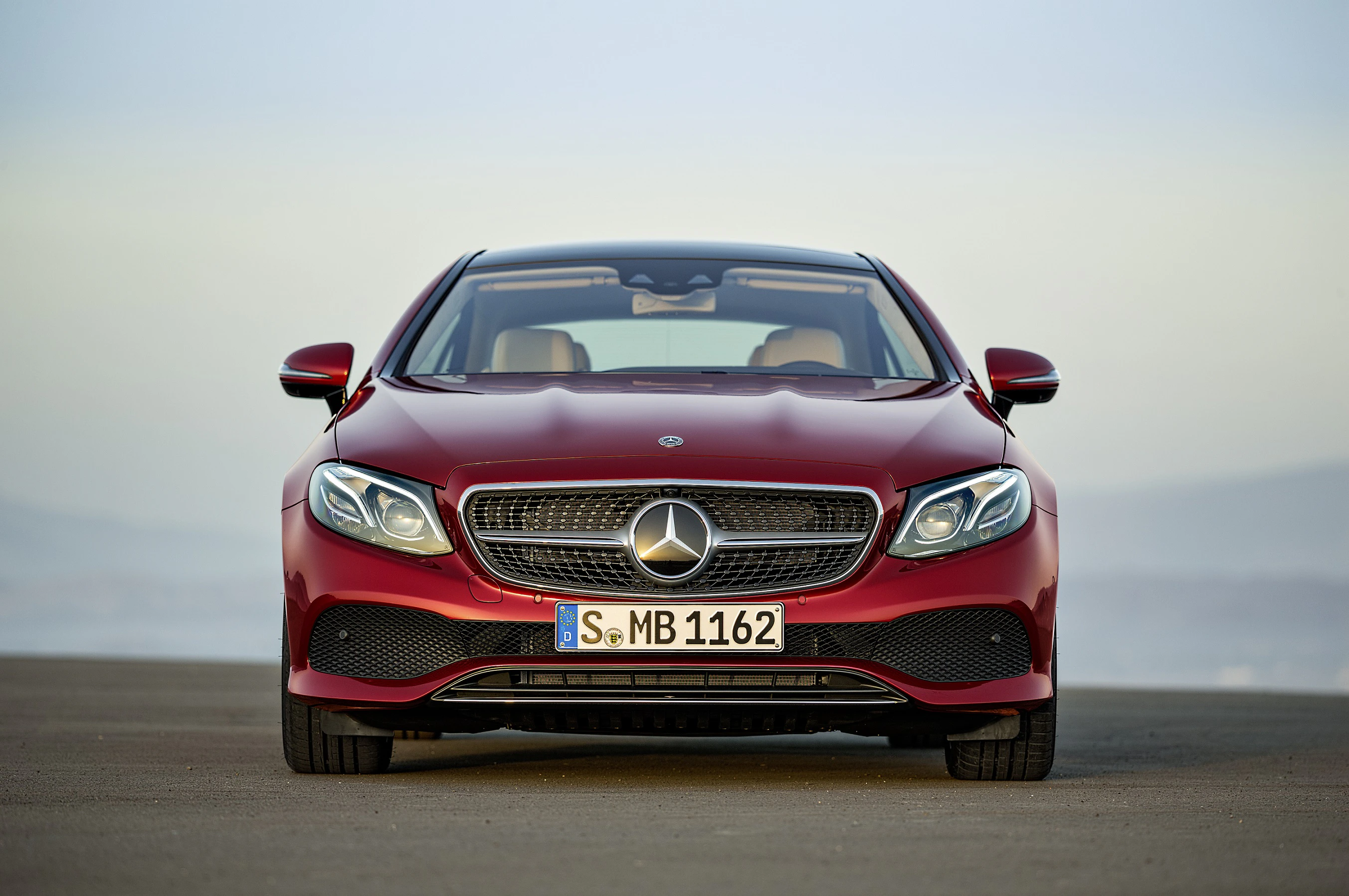 Rotes Auto, frontal fotografiert, auf freier Fläche. Mercedes-Stern auf dem Kühlergrill, Kennzeichen erkennbar.