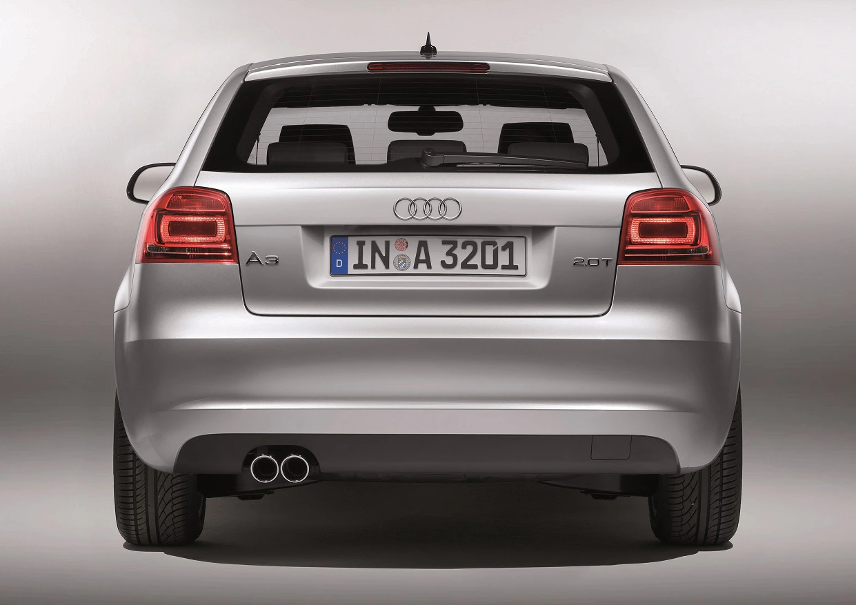 Rückansicht eines silbernen Audi A3 mit Doppelauspuff und deutschen Kennzeichen, auf grauem Hintergrund.