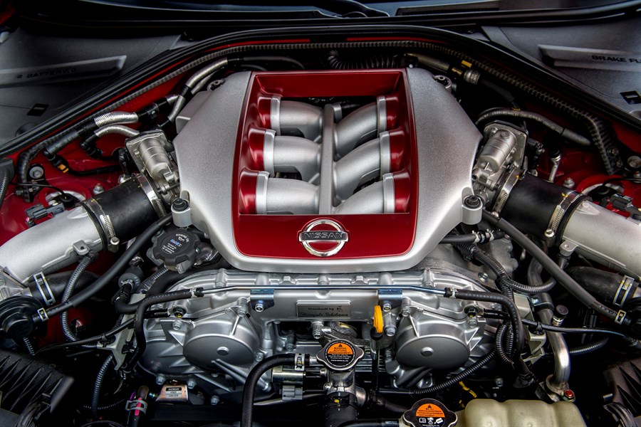 Motor eines Nissan GT-R: Komplexe Motorkonstruktion mit sichtbarem Nissan-Logo, silbernen und roten Komponenten sowie schwarzen Schläuchen.