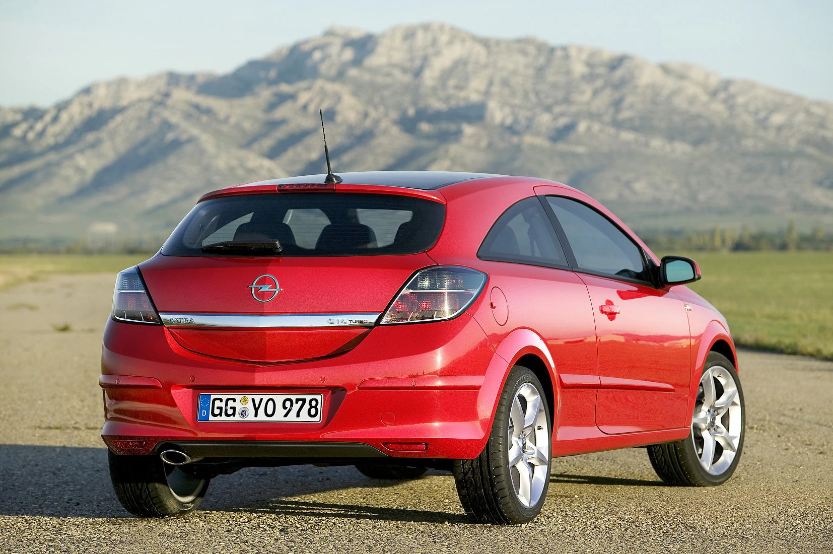 Roter Opel Astra auf einer Straße vor einer Bergkulisse bei klarem Himmel.