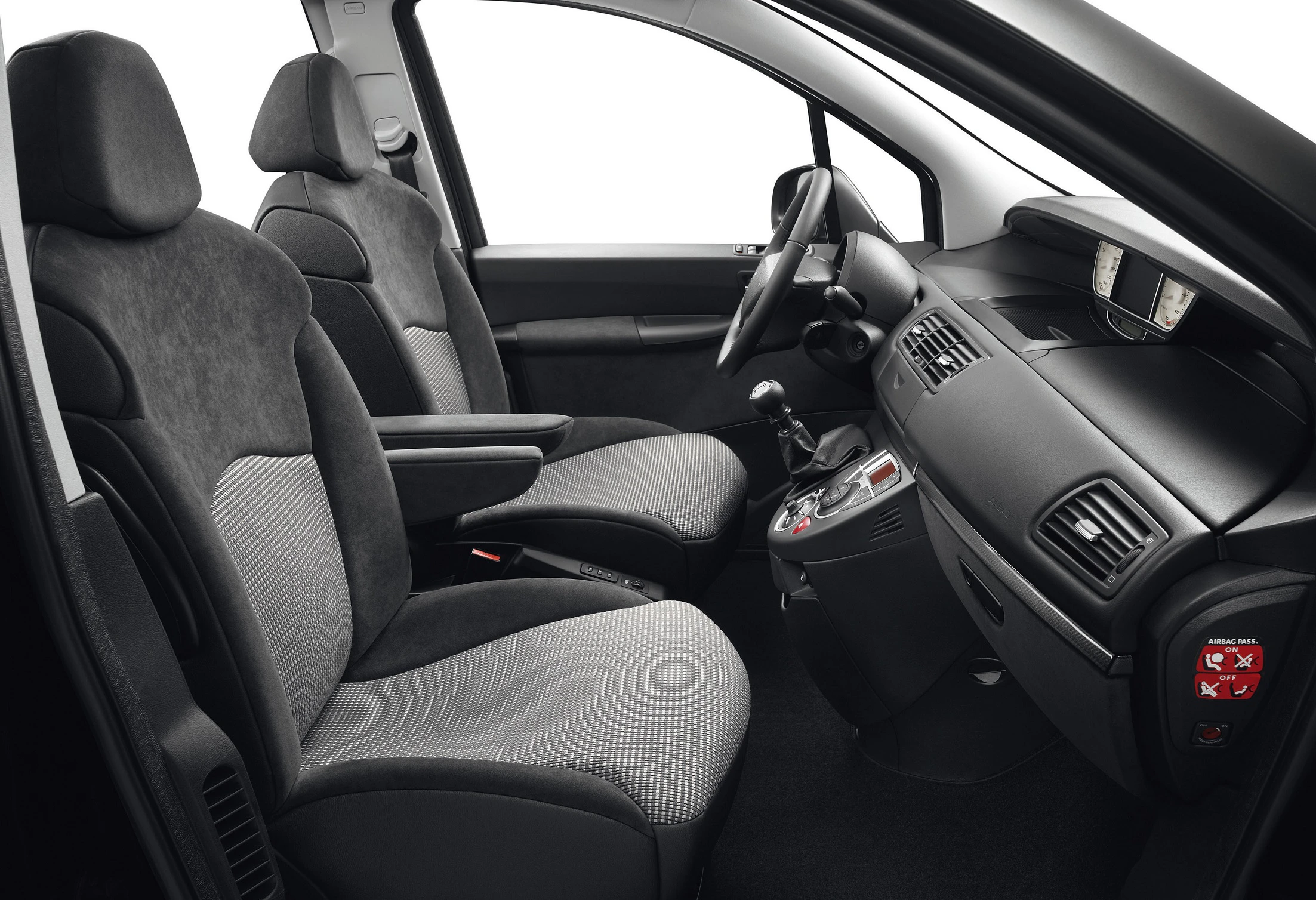 Innenraum eines Autos mit zwei vorderen Sitzen, modernem Armaturenbrett und Schalthebel; Polster in Schwarz und Grau.
