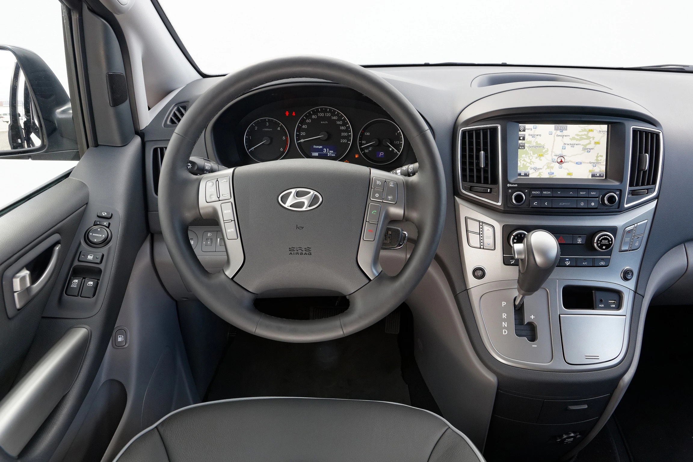 Lenkrad und Armaturenbrett eines Hyundai-Fahrzeugs mit integriertem Navigationssystem, Geschwindigkeitsmesser und Gangschaltung.