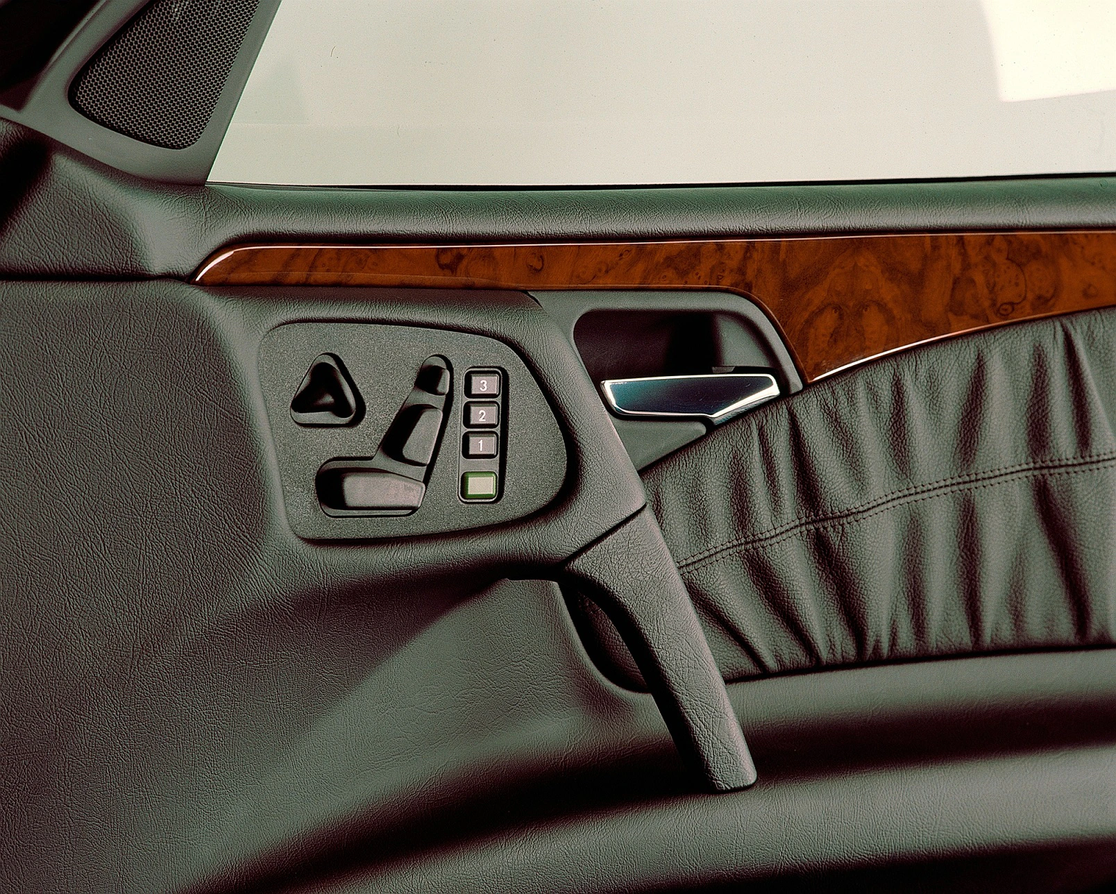 Nahaufnahme einer Autotürverkleidung mit Holzverzierung, elektrischen Sitzverstellknöpfen und Türgriff. Luxuriöses Design.