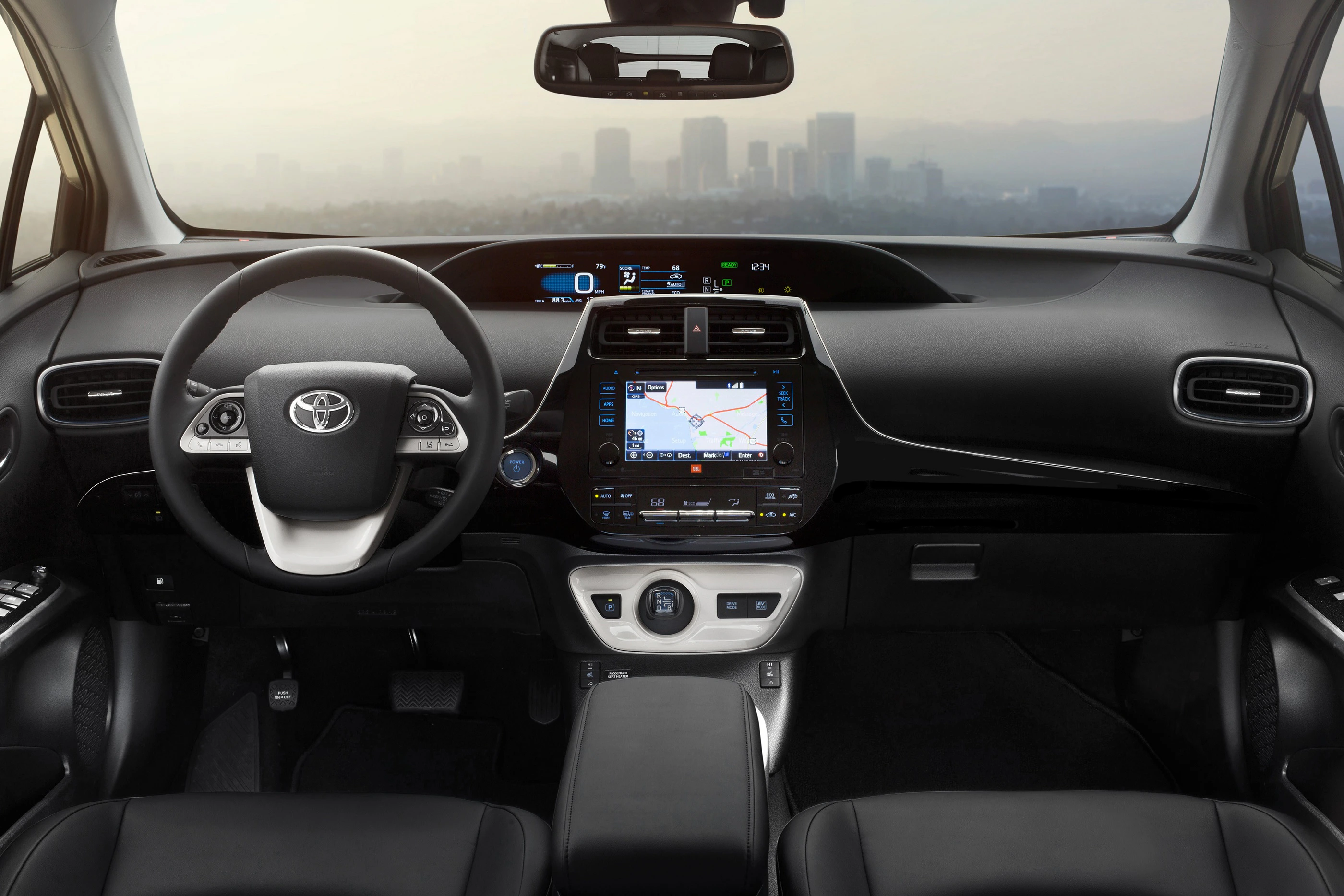 Innenraum eines Autos mit schwarzem Armaturenbrett, Touchscreen-Navigationssystem und Stadtblick durch die Windschutzscheibe.