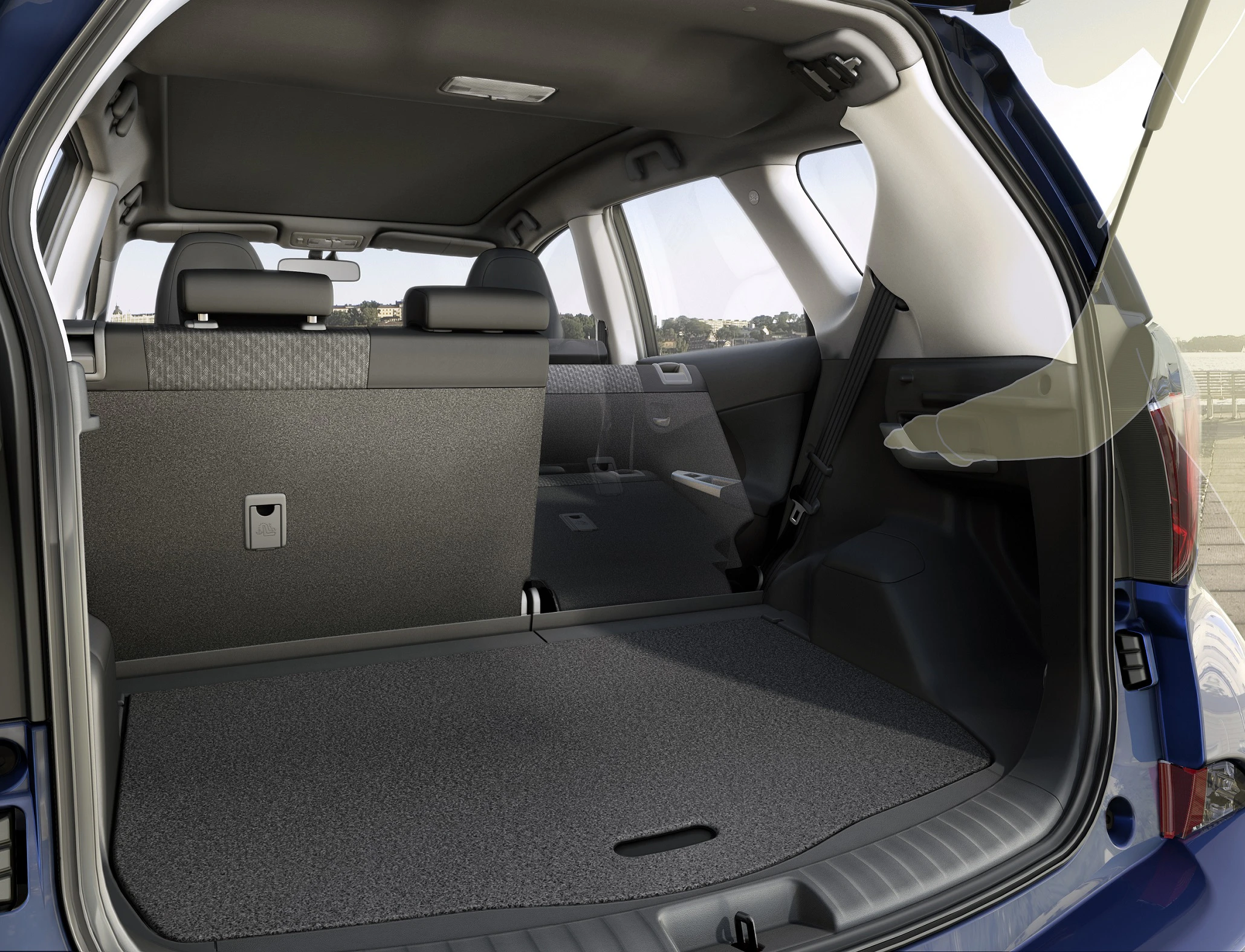 Kofferraum eines Autos mit umgeklappten Rücksitzen. Der Innenraum ist geräumig und der Boden hat einen grauen Teppich.