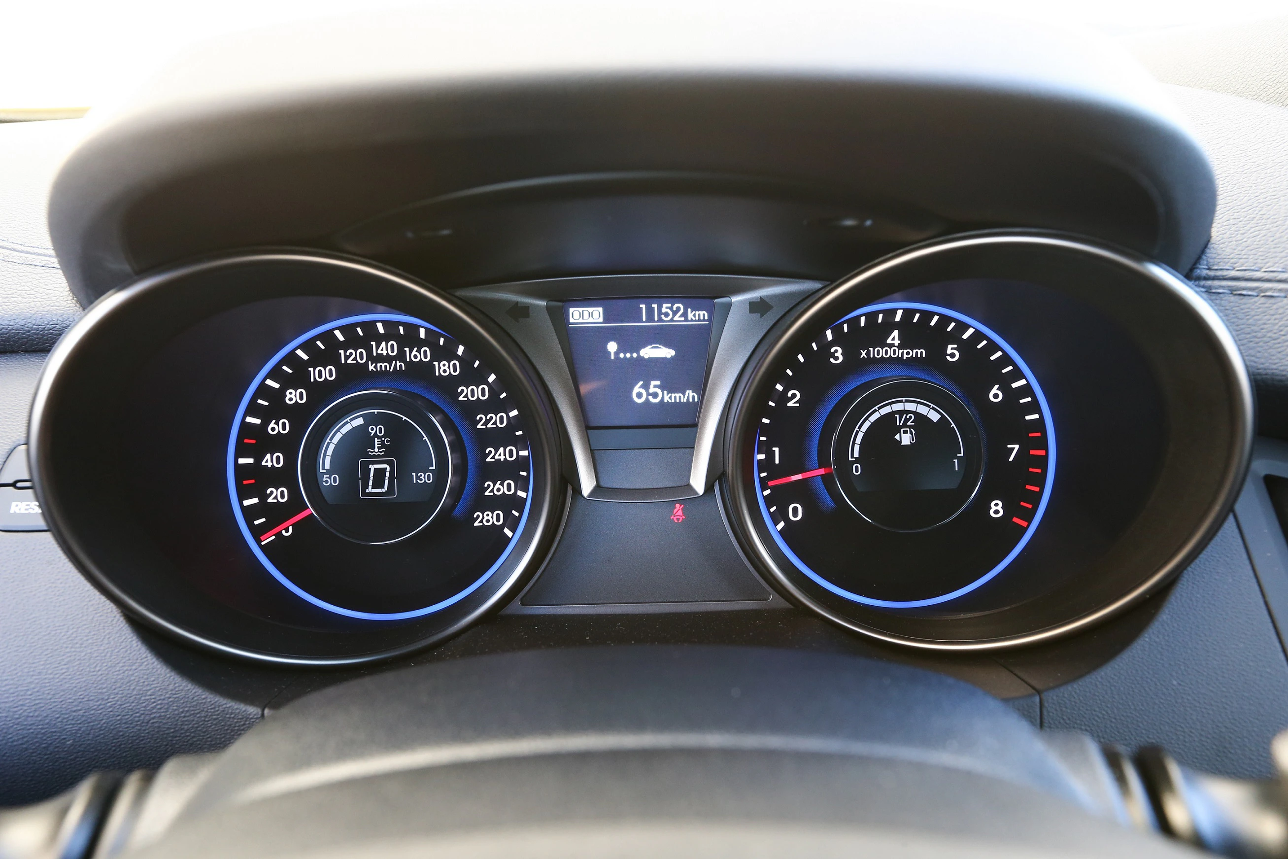 Nahaufnahme eines Tachometers und Drehzahlmessers eines Autos, zeigt 65 km/h und 1152 km. Anzeige von Tank- und Temperaturstatus.