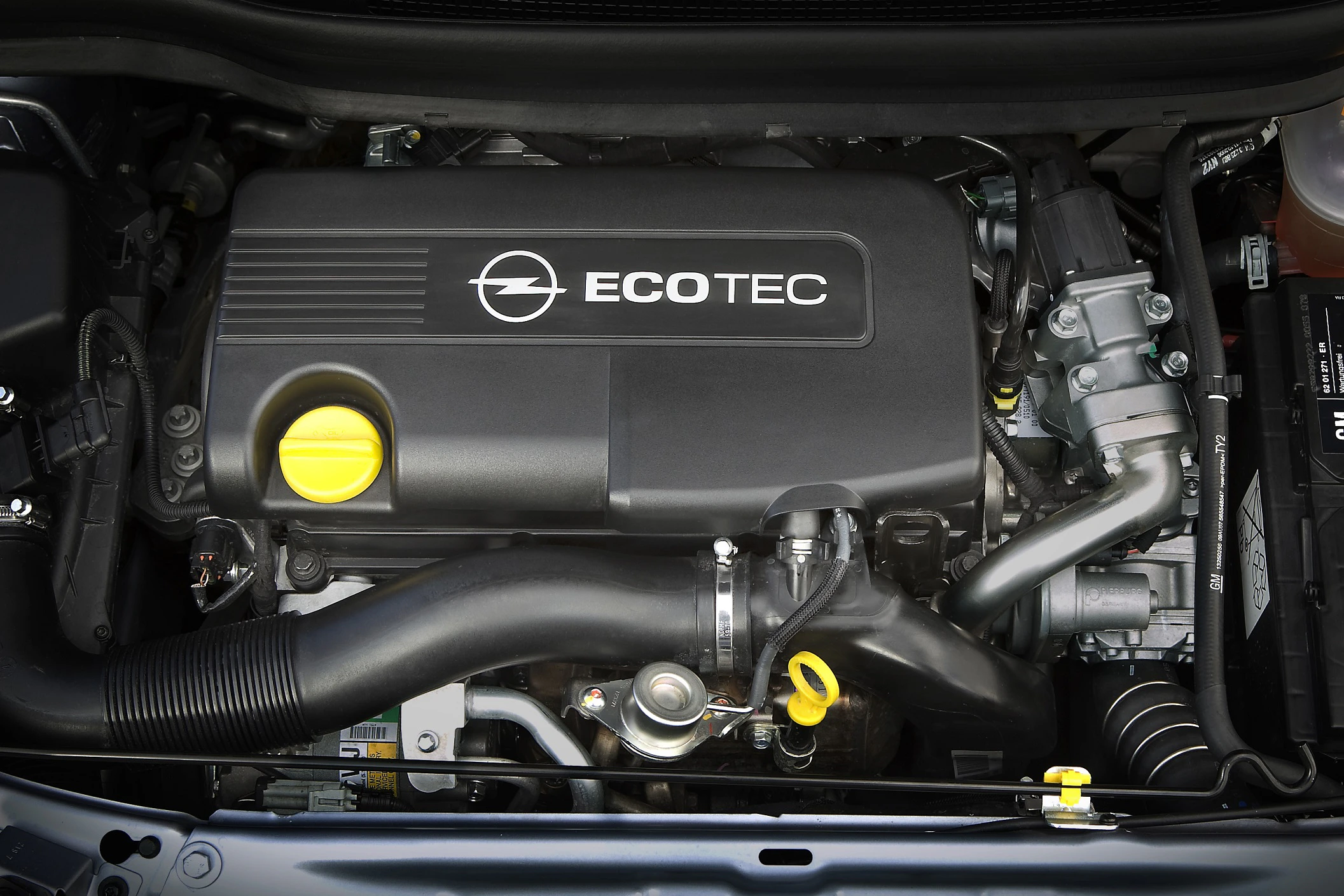 Opel-Motor mit "ECO TEC" Schriftzug, schwarzer Motorabdeckung, sichtbaren Rohren und gelben Öldeckeln.