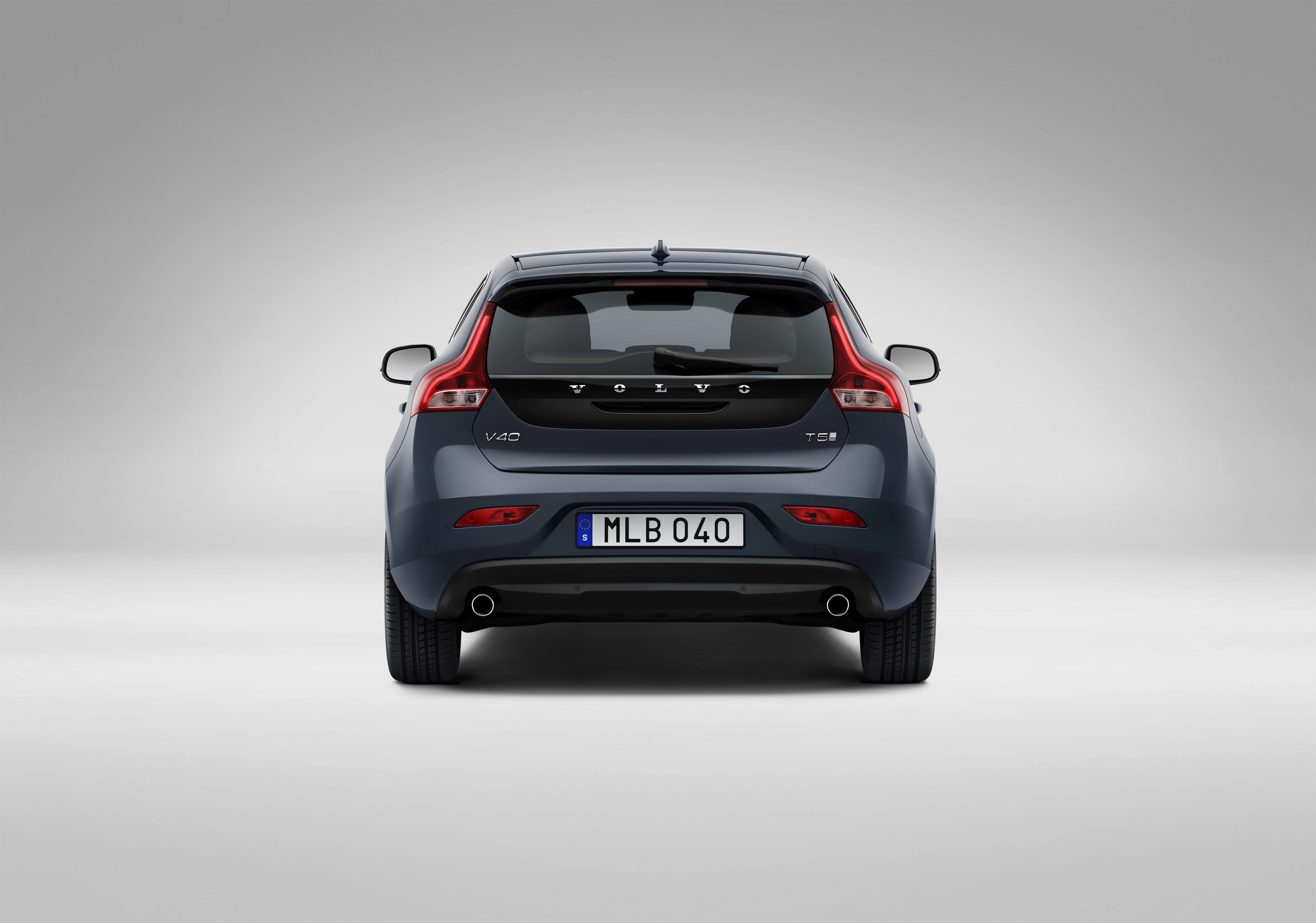 Rückansicht eines grauen Volvo V40 T5 mit sichtbaren Auspuffrohren und Kennzeichen auf neutralem Hintergrund.