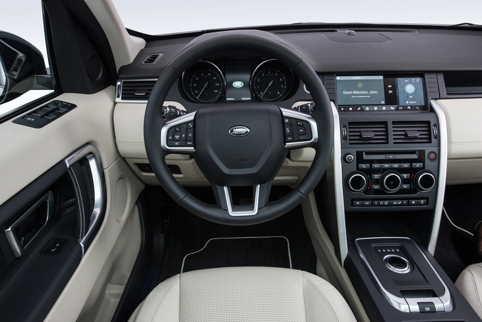 Lenkrad und Armaturenbrett eines modernen Autos mit Touchscreen, Tachometern und Bedienelementen, helles Interieur.