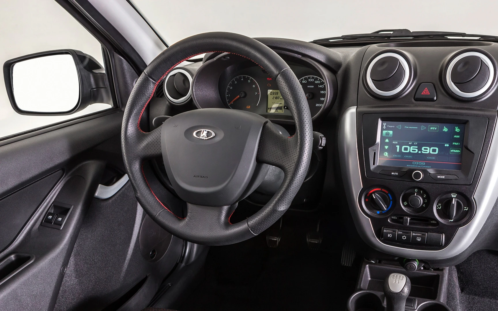 Innenraum eines Autos mit Lenkrad, Tachometer, Lüftungsdüsen und digitalem Radiodisplay. Moderne, schlichte Gestaltung.