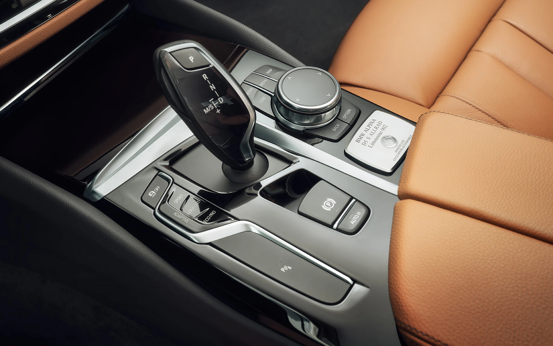 Nahaufnahme einer luxuriösen Auto-Mittelkonsole mit Schalthebel, braunen Ledersitzen und Bedienelementen.