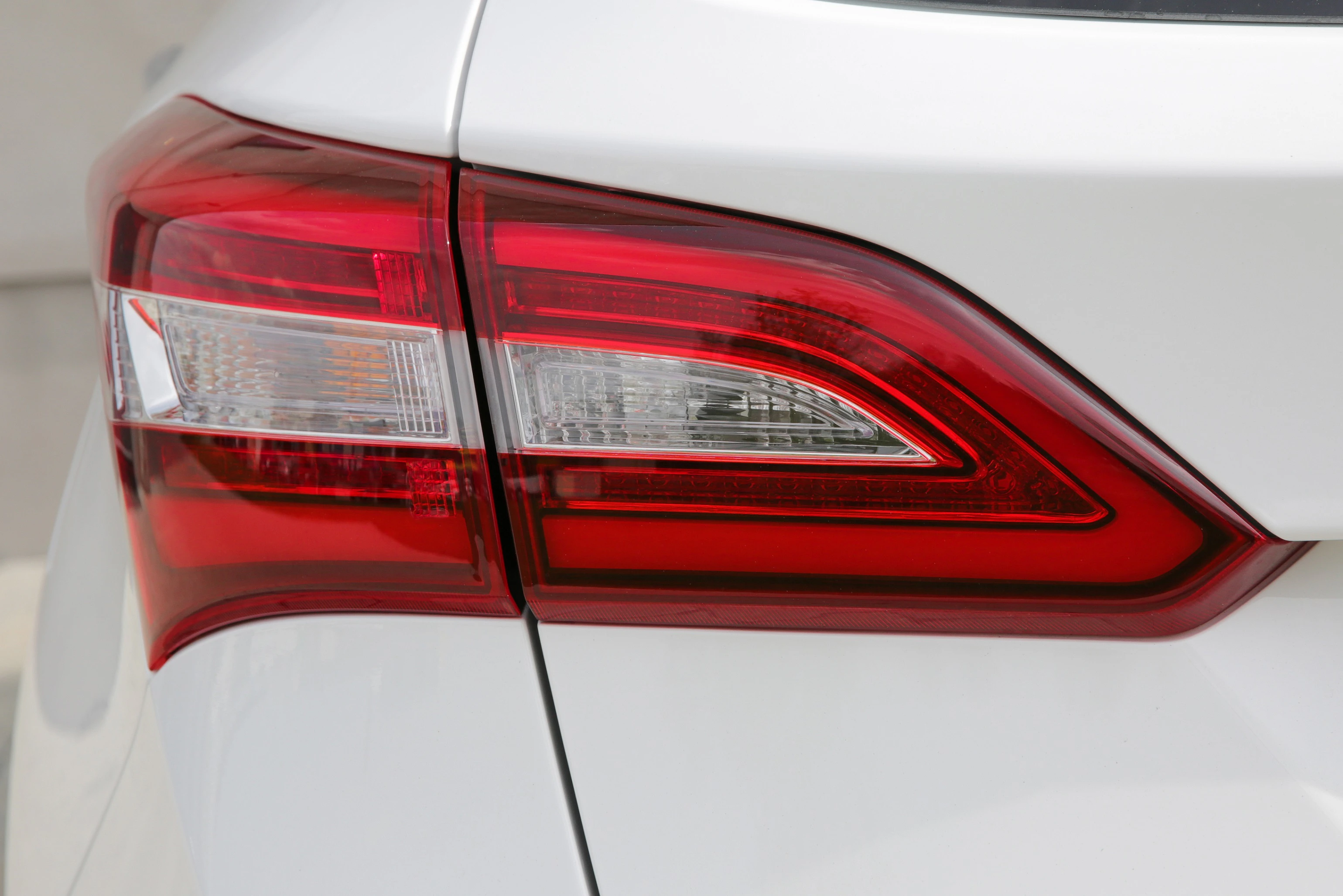 Nahaufnahme eines weißen Autos mit leuchtend rotem Rücklicht und klaren Linien, die den modernen Stil des Fahrzeugs betonen.