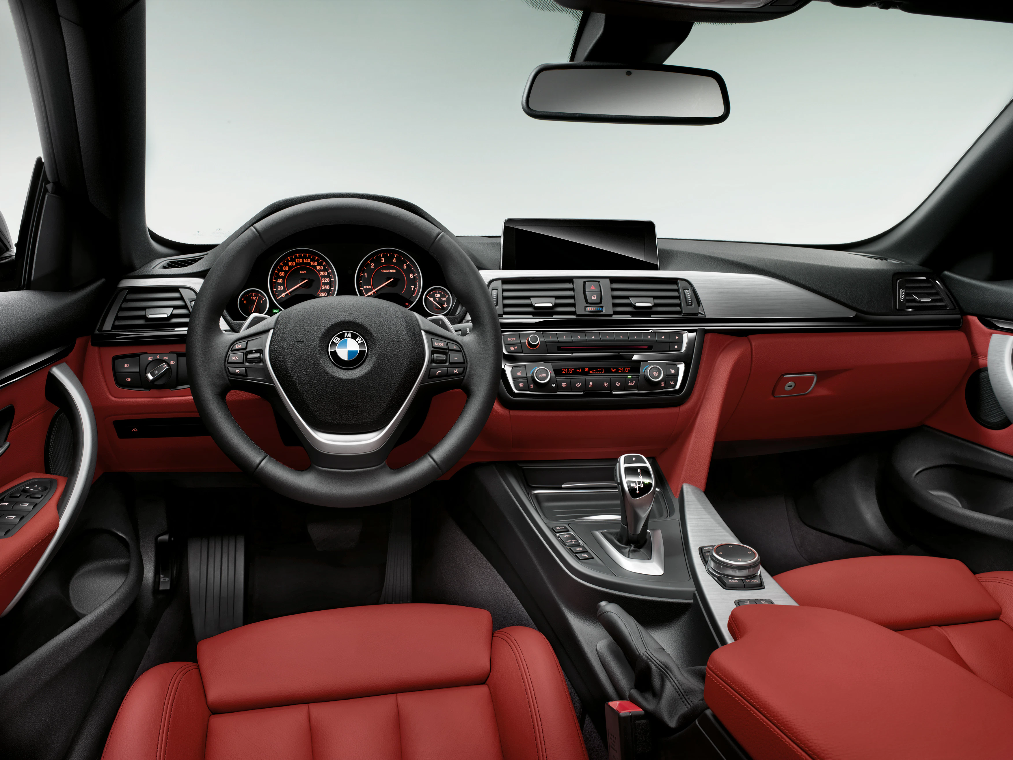 Innenraum eines BMW mit rotem Leder, Multifunktionslenkrad, digitalem Armaturenbrett und moderner Mittelkonsole.