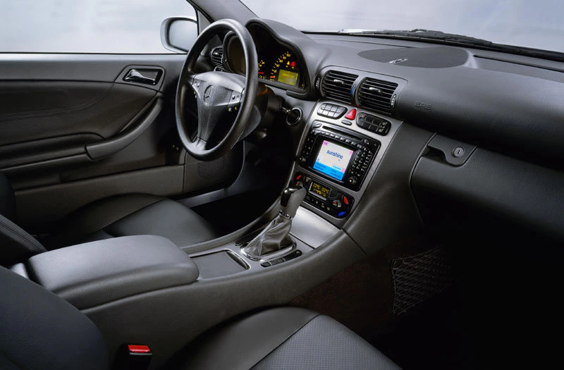Innenraum eines Autos mit grauen Ledersitzen, Armaturenbrett mit eingebautem Bildschirm und Mittelkonsole. Automatikgetriebe sichtbar.