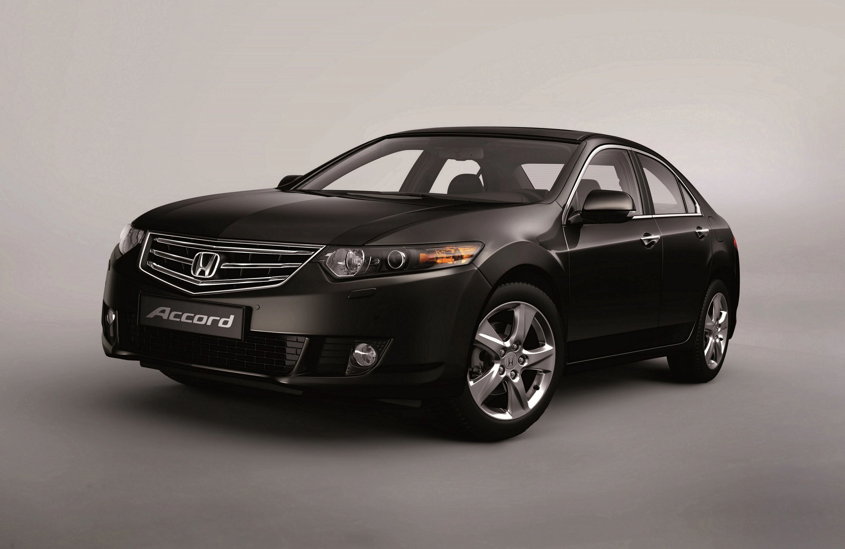 Schwarzer Honda Accord Limousine, seitlich von vorne fotografiert, auf grauem Hintergrund.