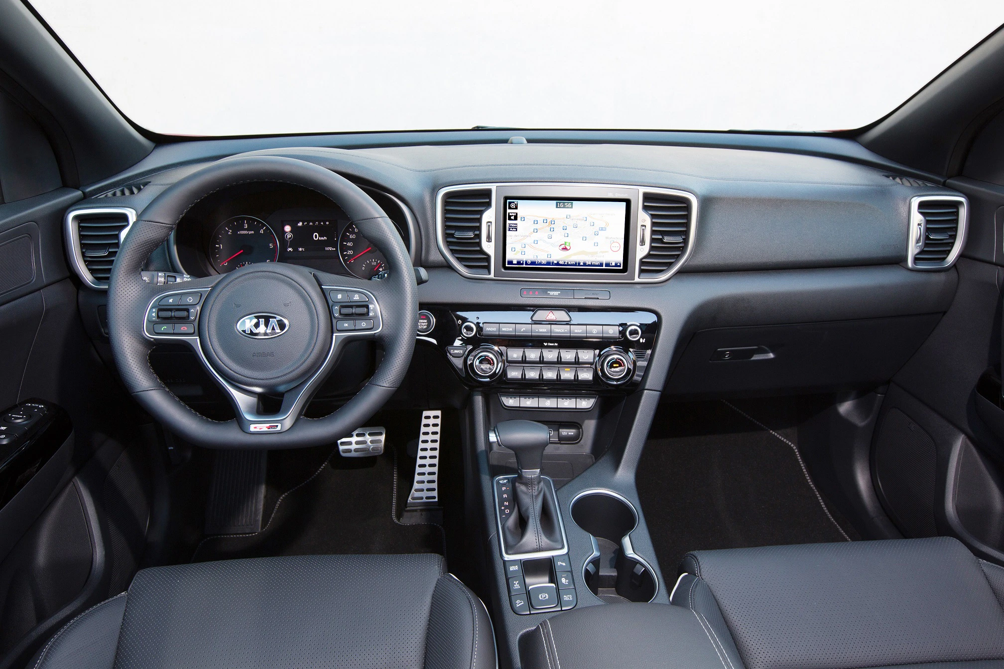 Innenraum eines Autos mit Lenkrad, Infotainment-Bildschirm, Tacho und Mittelkonsole mit Schalthebel. Modernes, funktionales Design.