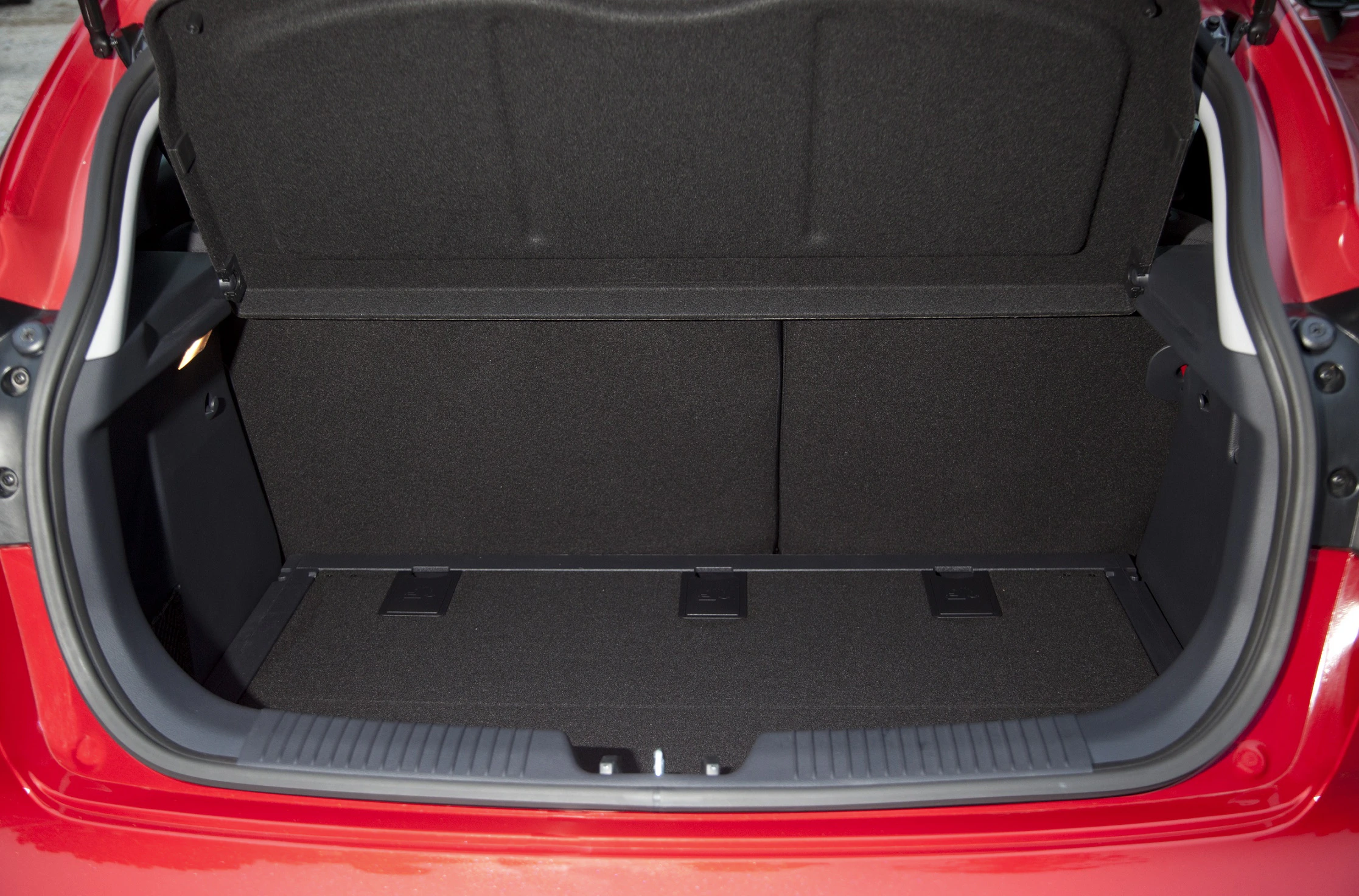 Roter Auto-Kofferraum, offen, zeigt geräumigen, leeren Innenbereich mit dunkler Polsterung. Ideal für Gepäck oder Einkäufe.