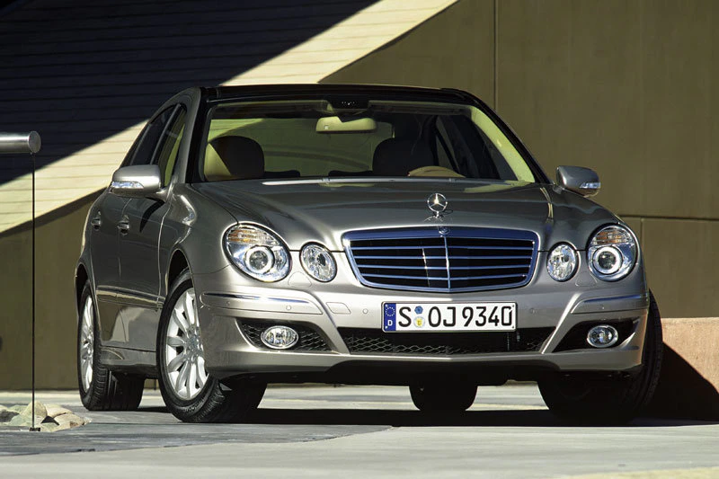 Silberner Mercedes-Benz E-Klasse steht vor einem modernen Gebäude. Frontalansicht mit sichtbarem Kennzeichen.